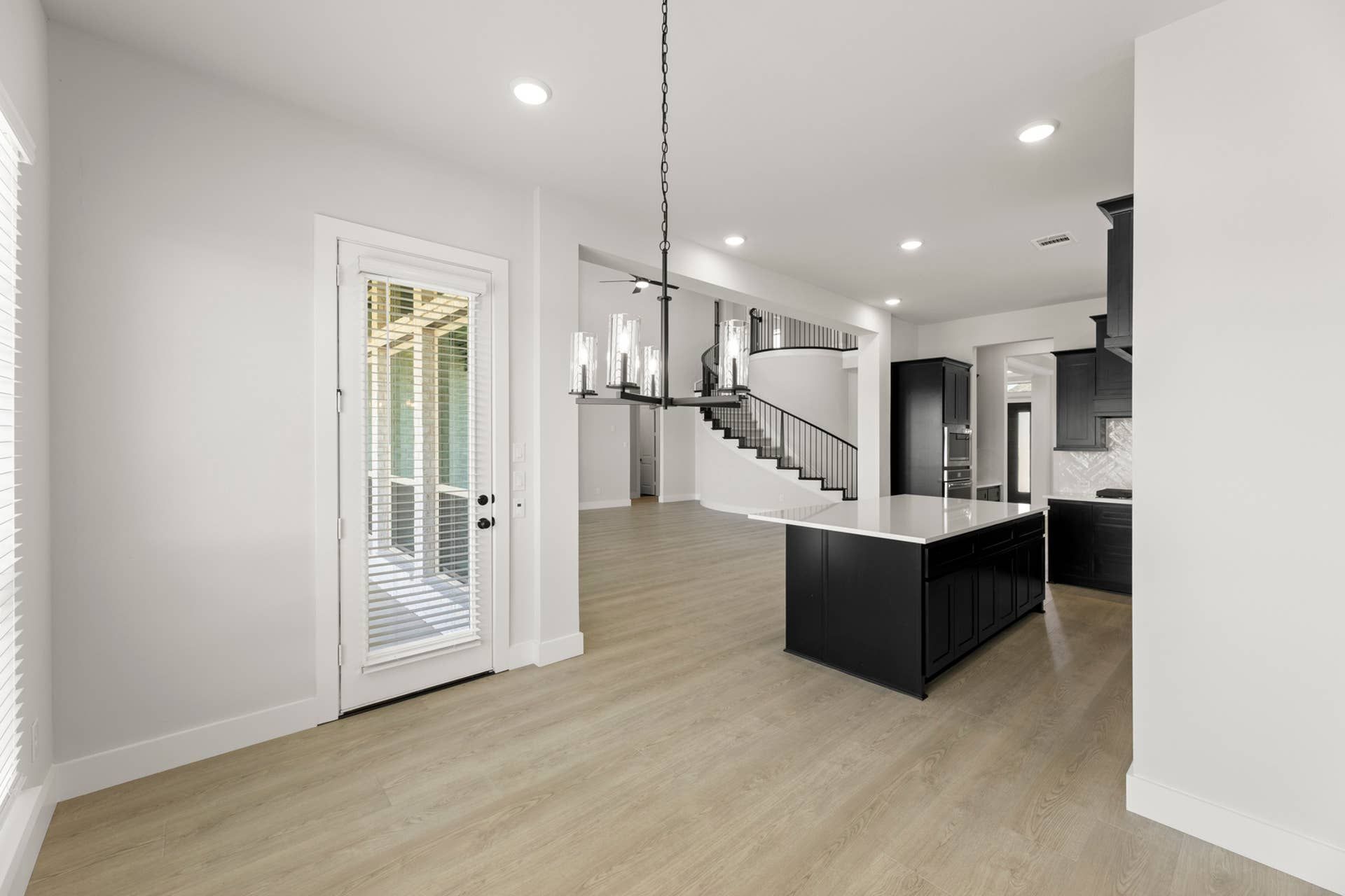 Modern open-plan kitchen with island, staircase, and natural light from patio door.
