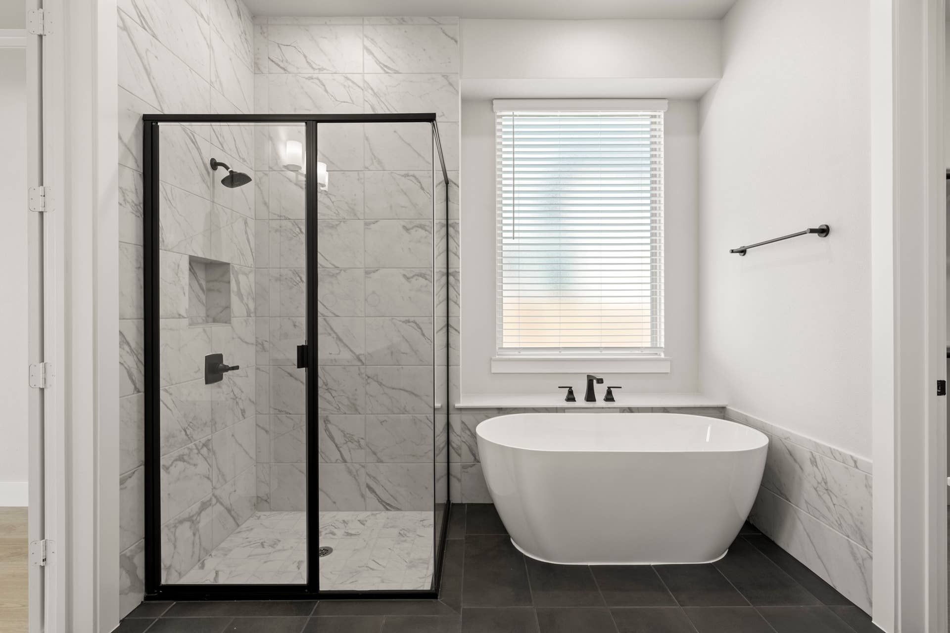 Modern bathroom with marble shower and freestanding bathtub.