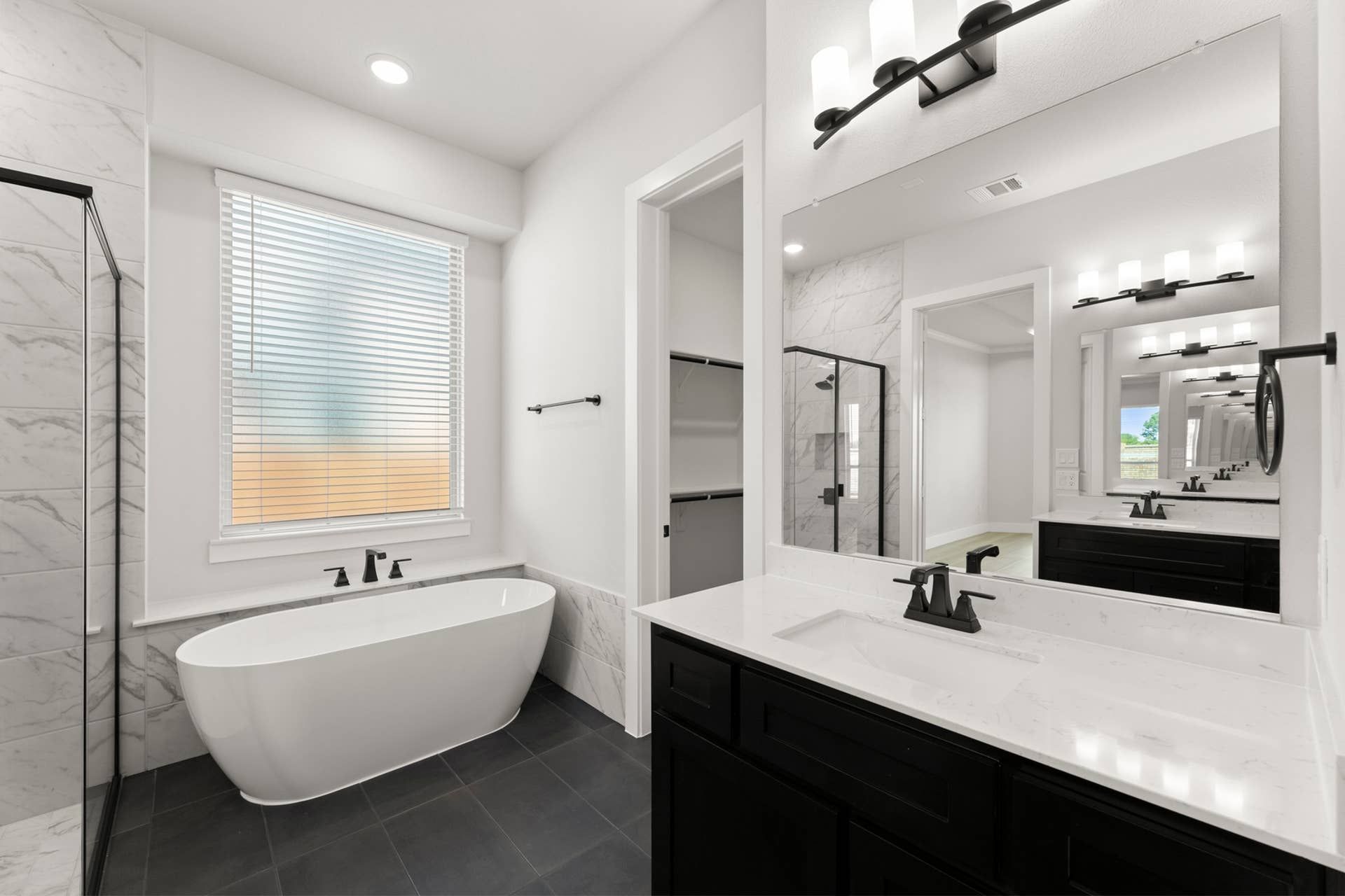 Modern bathroom with freestanding tub, black fixtures, and marble accents.