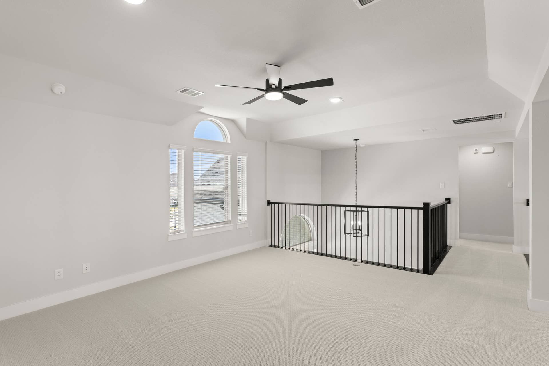 Bright loft area with modern ceiling fan and stylish railing.