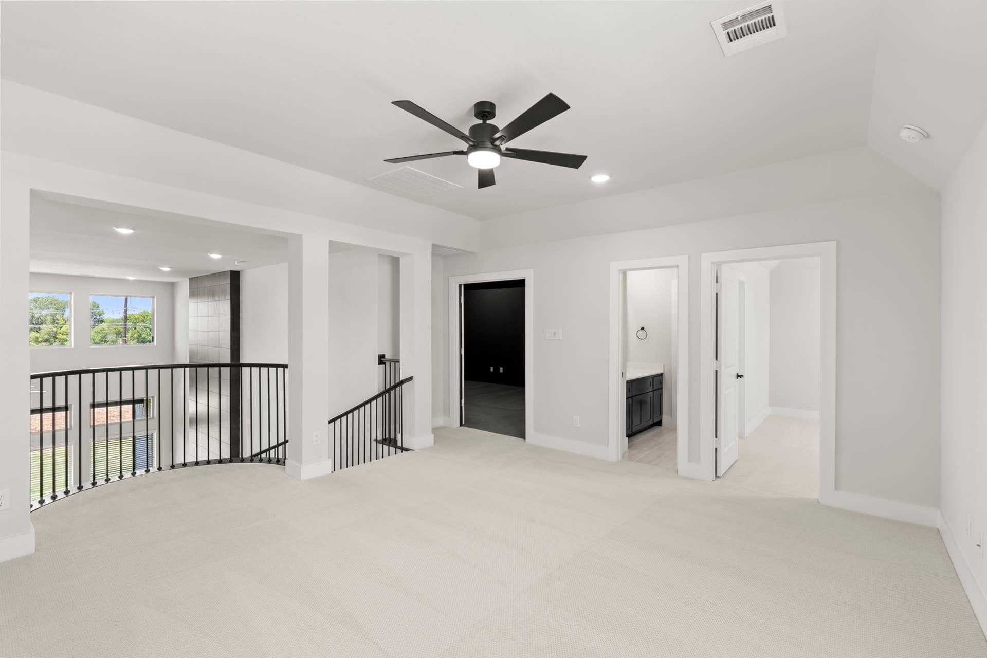 Spacious open-concept loft with ceiling fan and modern railing overlooking lower level.