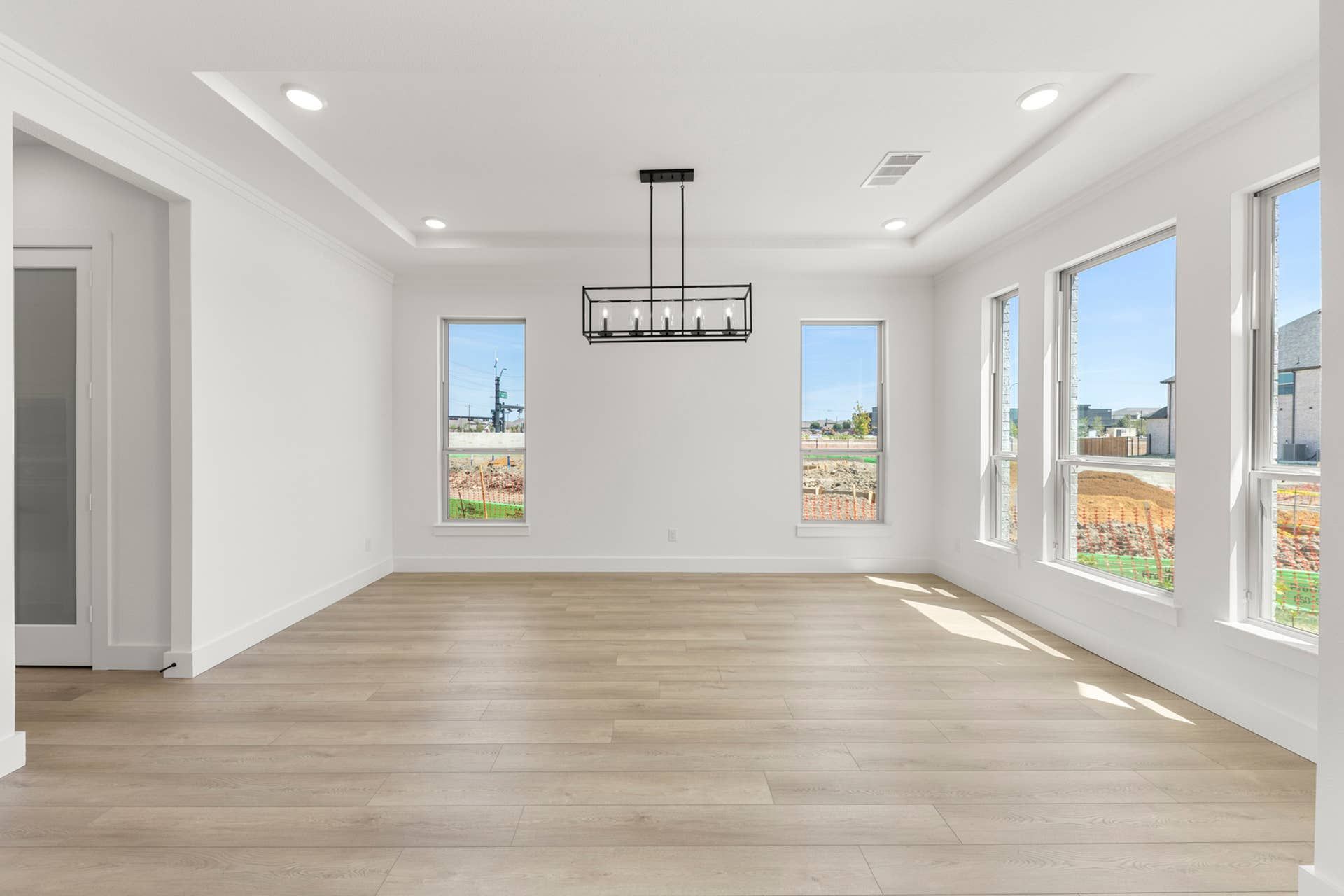 Spacious dining room with modern chandelier and large windows.