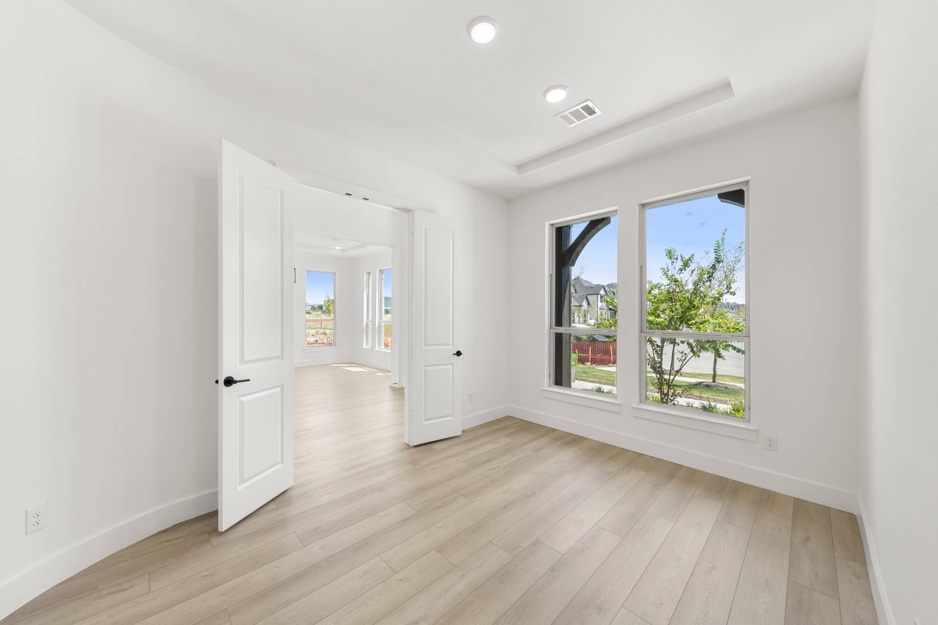 Bright study room with wooden floors and large windows overlooking garden.