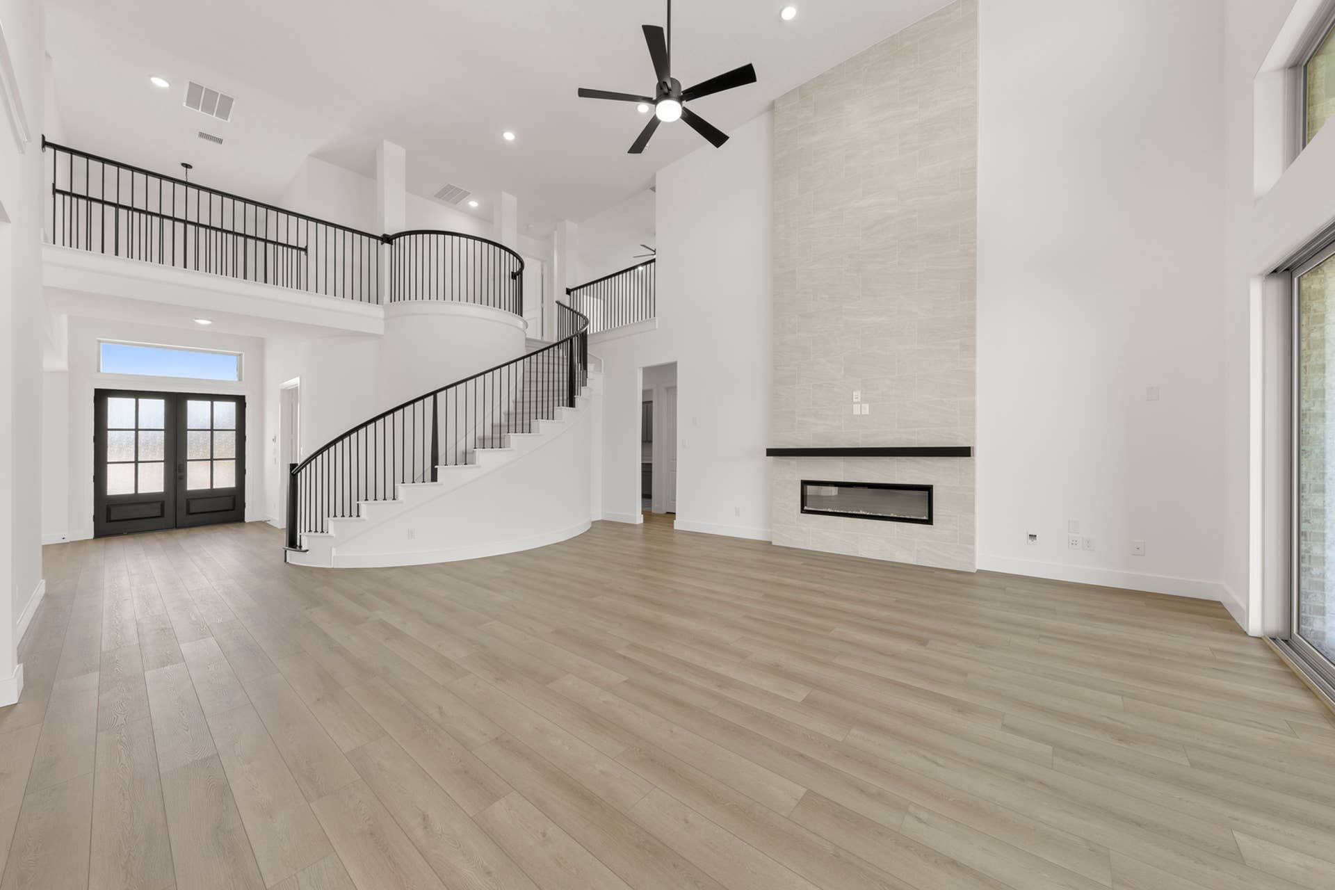 Spacious modern interior with elegant staircase, high ceiling, and sleek fireplace.