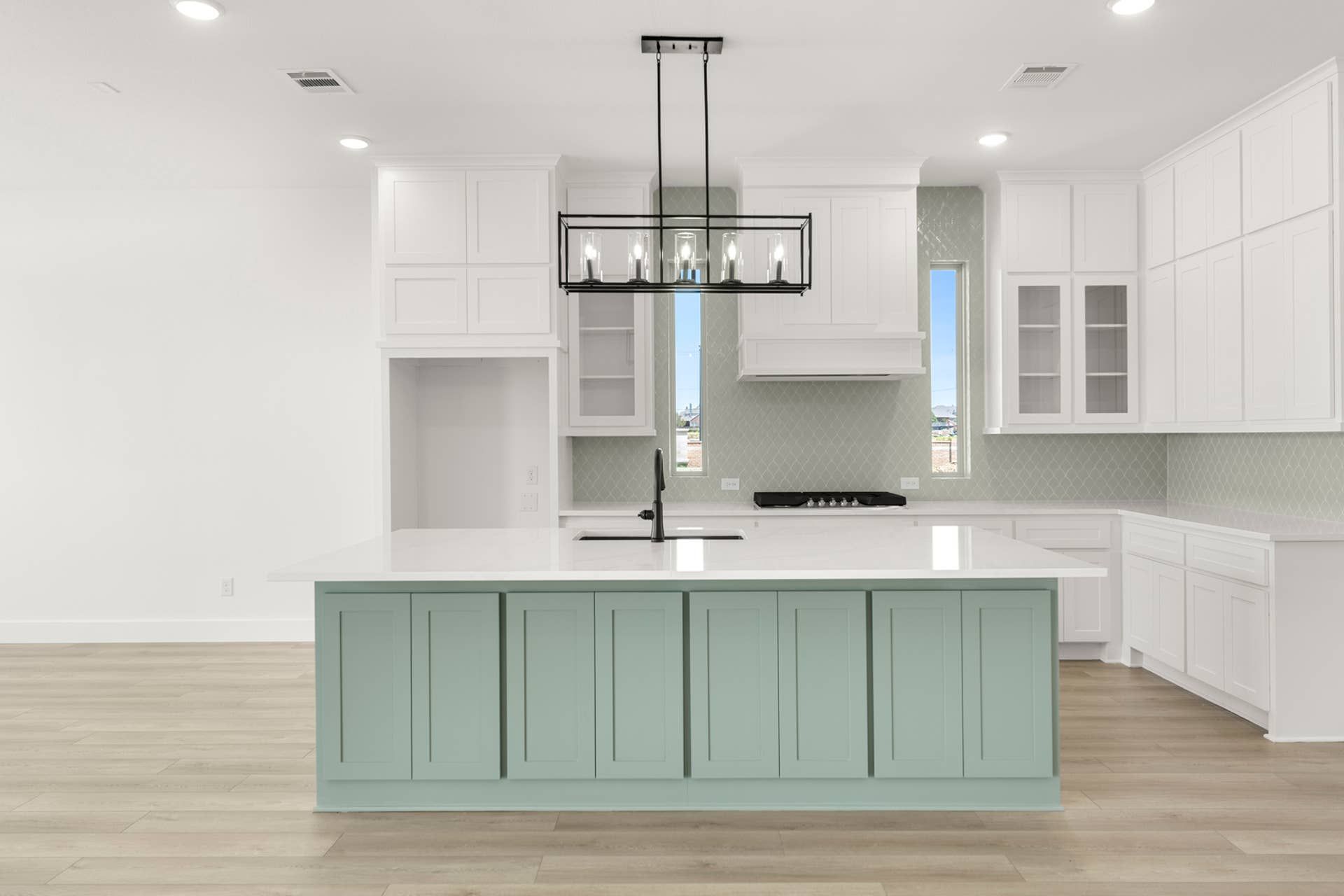 Modern kitchen with mint green island, white cabinets, and pendant lighting.