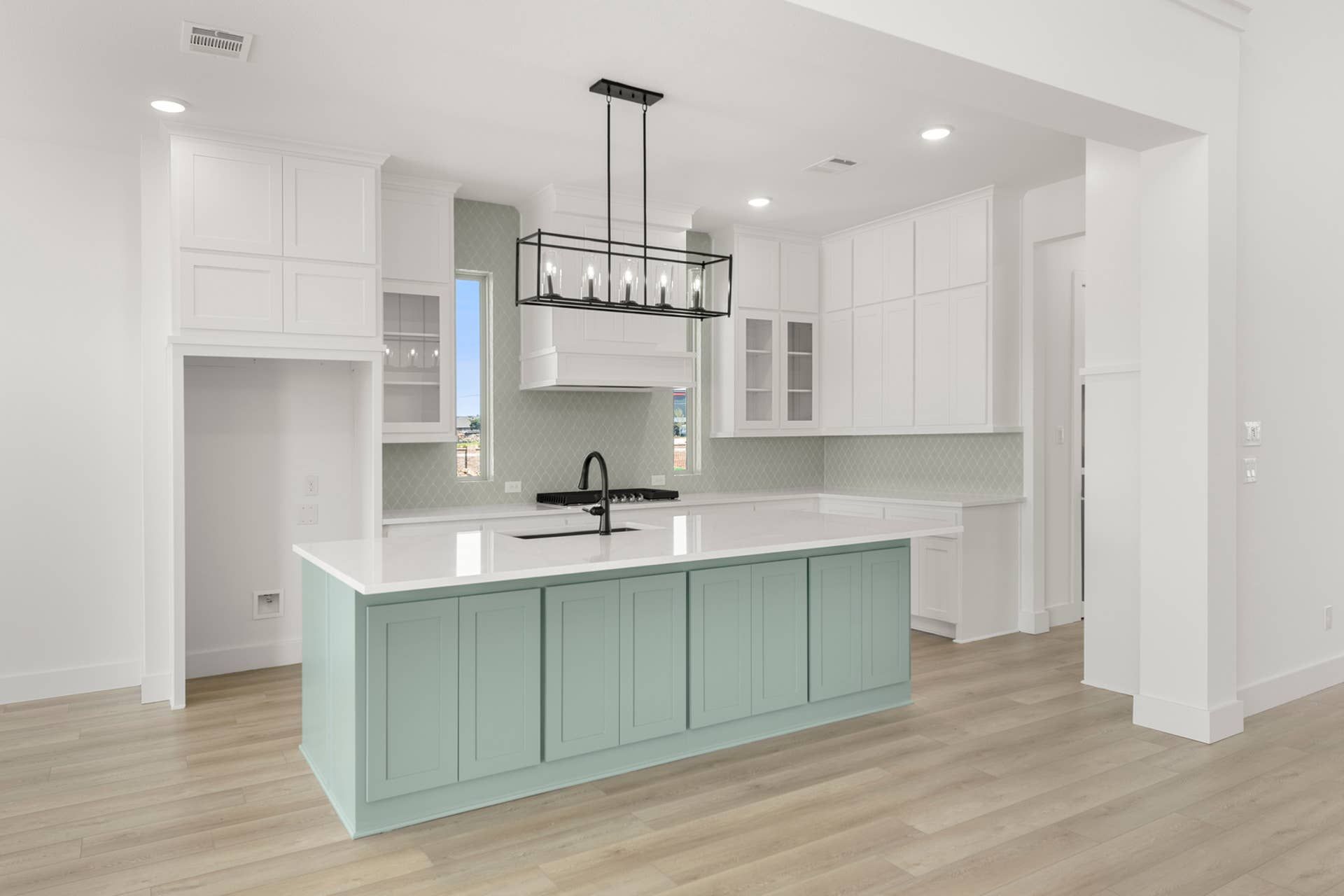 Modern kitchen with mint green island, white cabinetry, and wood flooring.