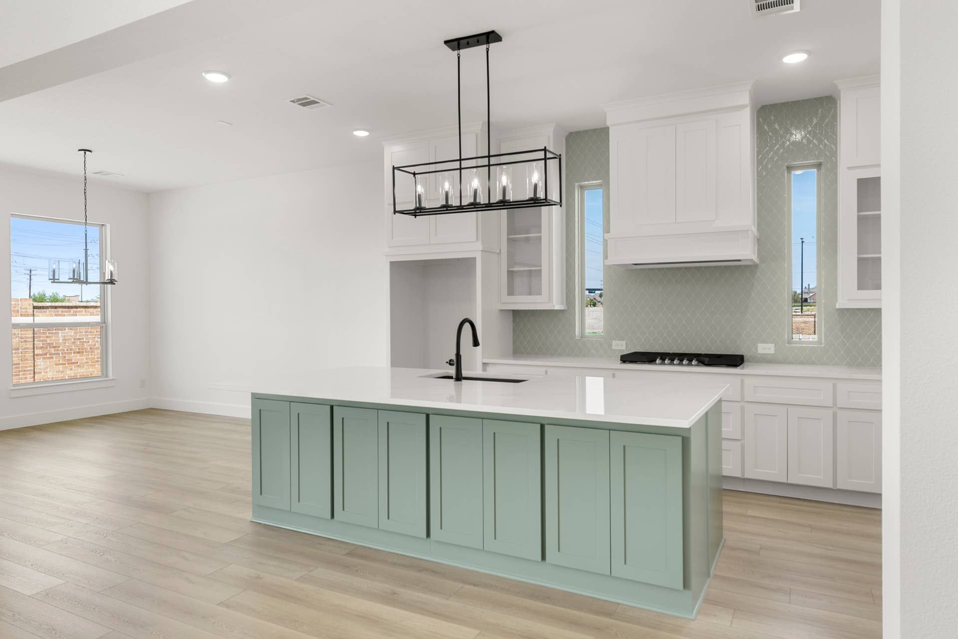 Modern kitchen with mint green island, white cabinetry, and pendant lighting.