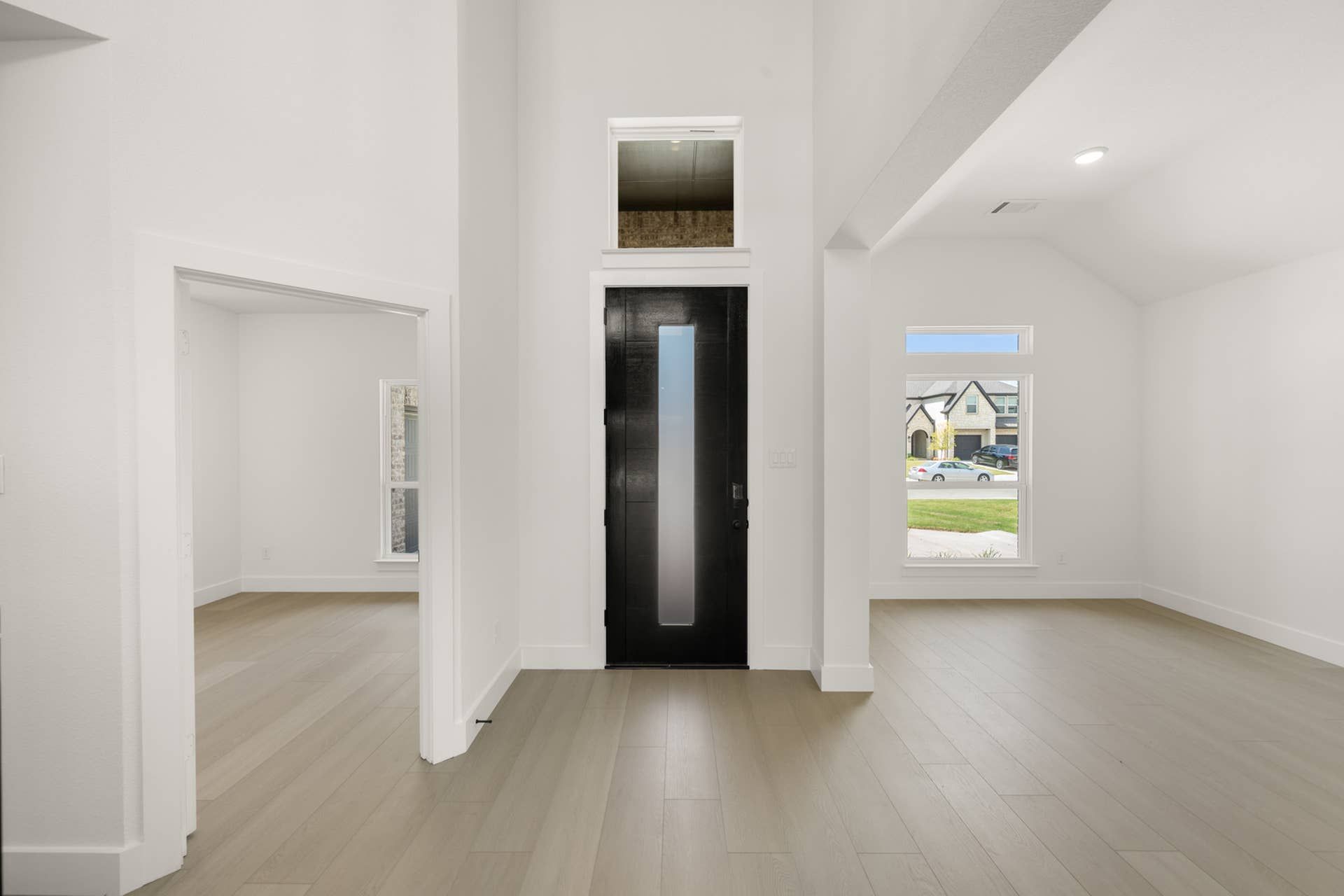 Modern entryway with tall ceilings and black front door.