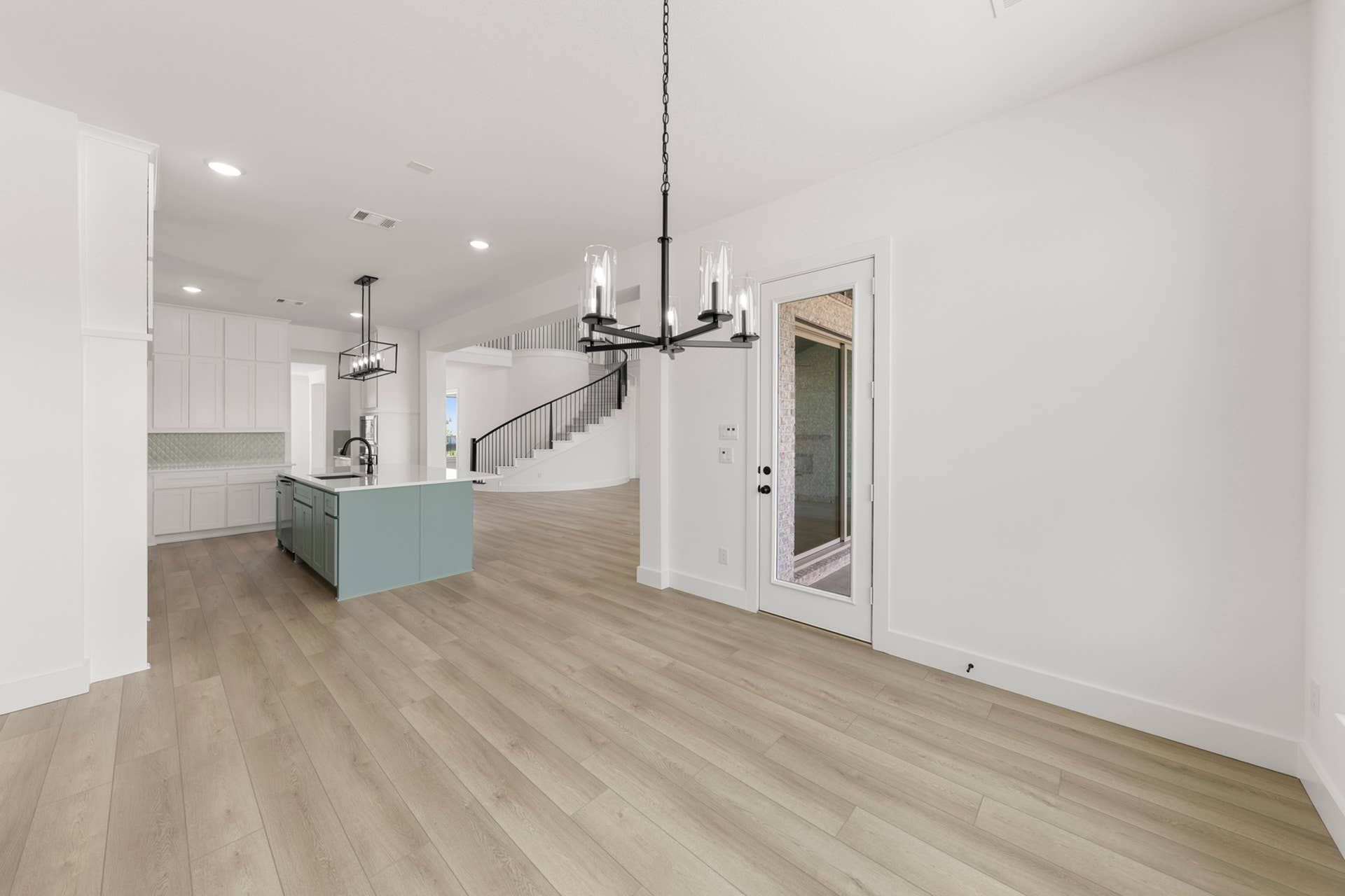 Spacious kitchen nook with modern chandelier and hardwood flooring.