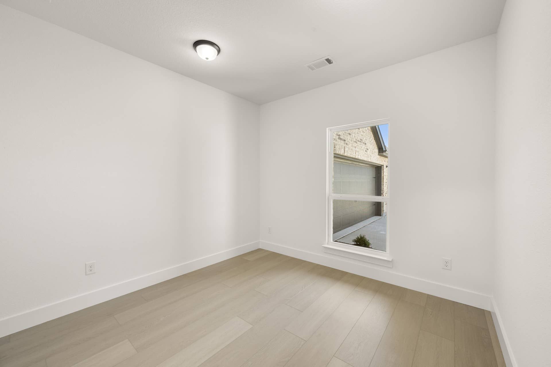 Minimalist study room with light wood flooring and single window view.