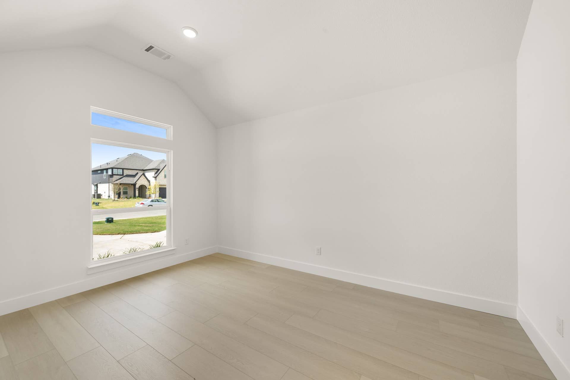 Bright interior space with large window and light wood flooring.