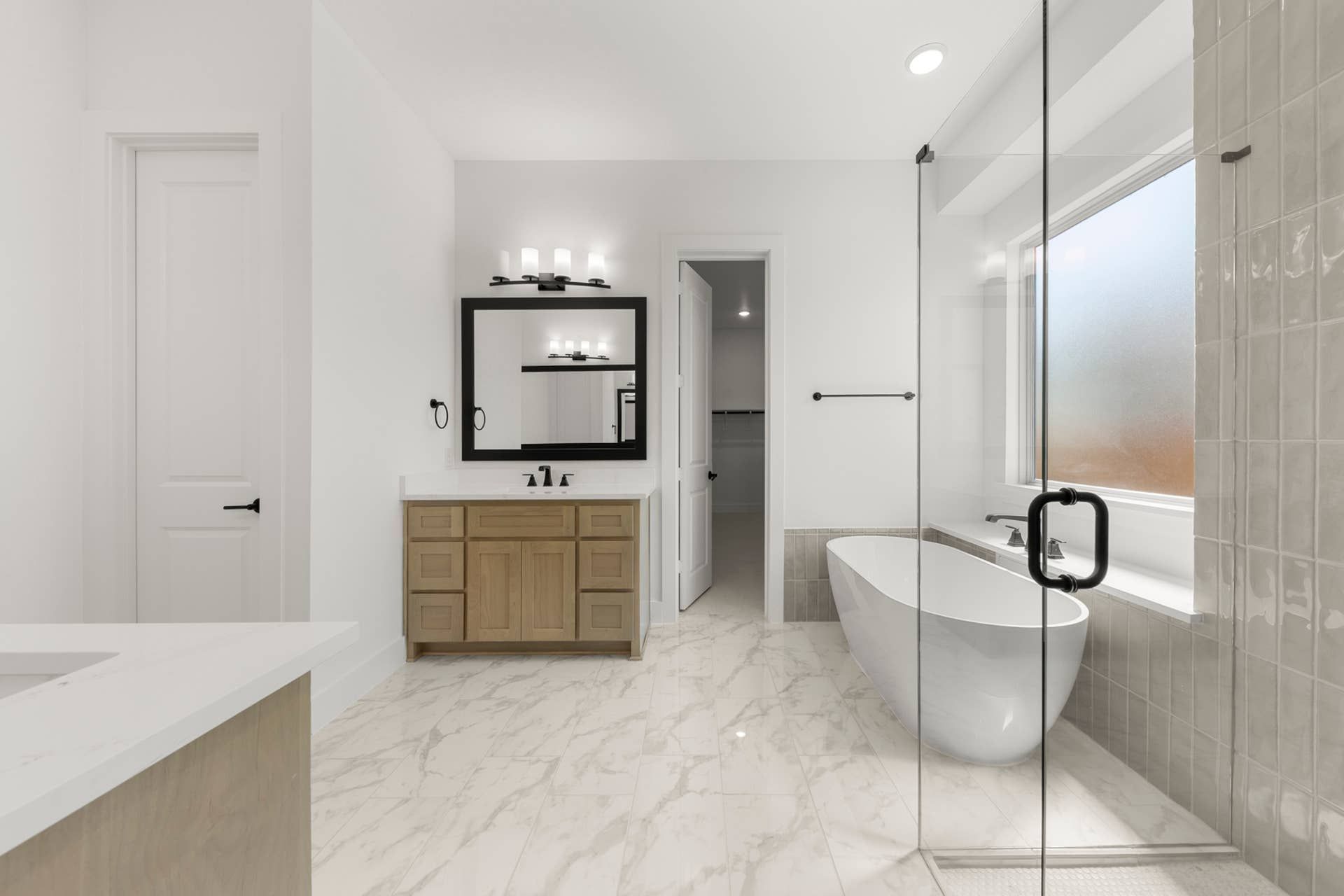 Modern bathroom with freestanding tub, glass shower, and marble tile flooring.