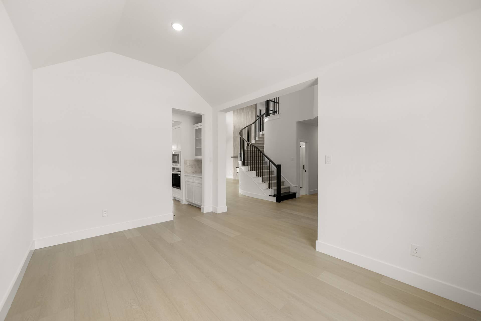 Spacious interior with light wood flooring and elegant curved staircase.