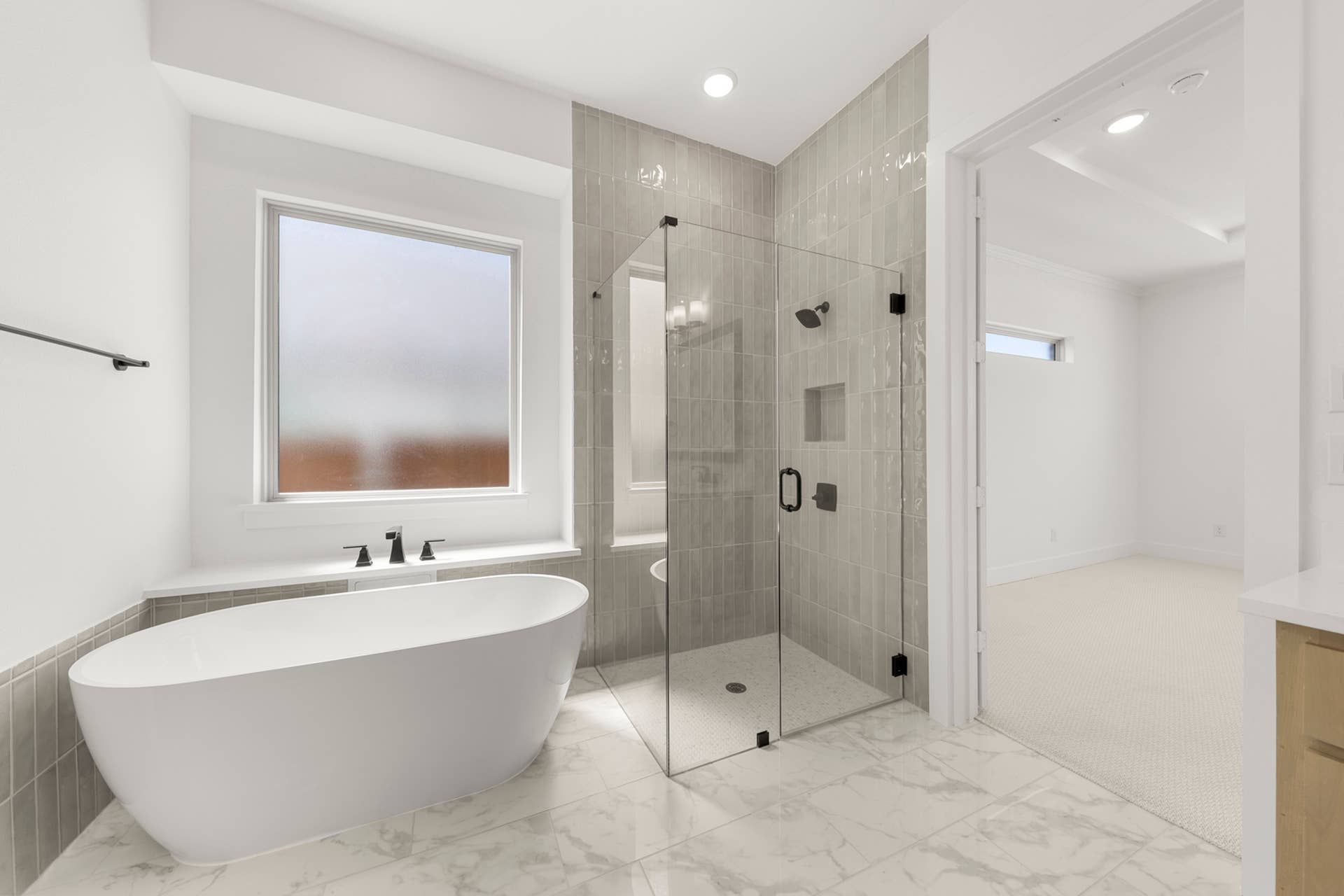 Modern bathroom with freestanding tub, glass shower, and frosted window.