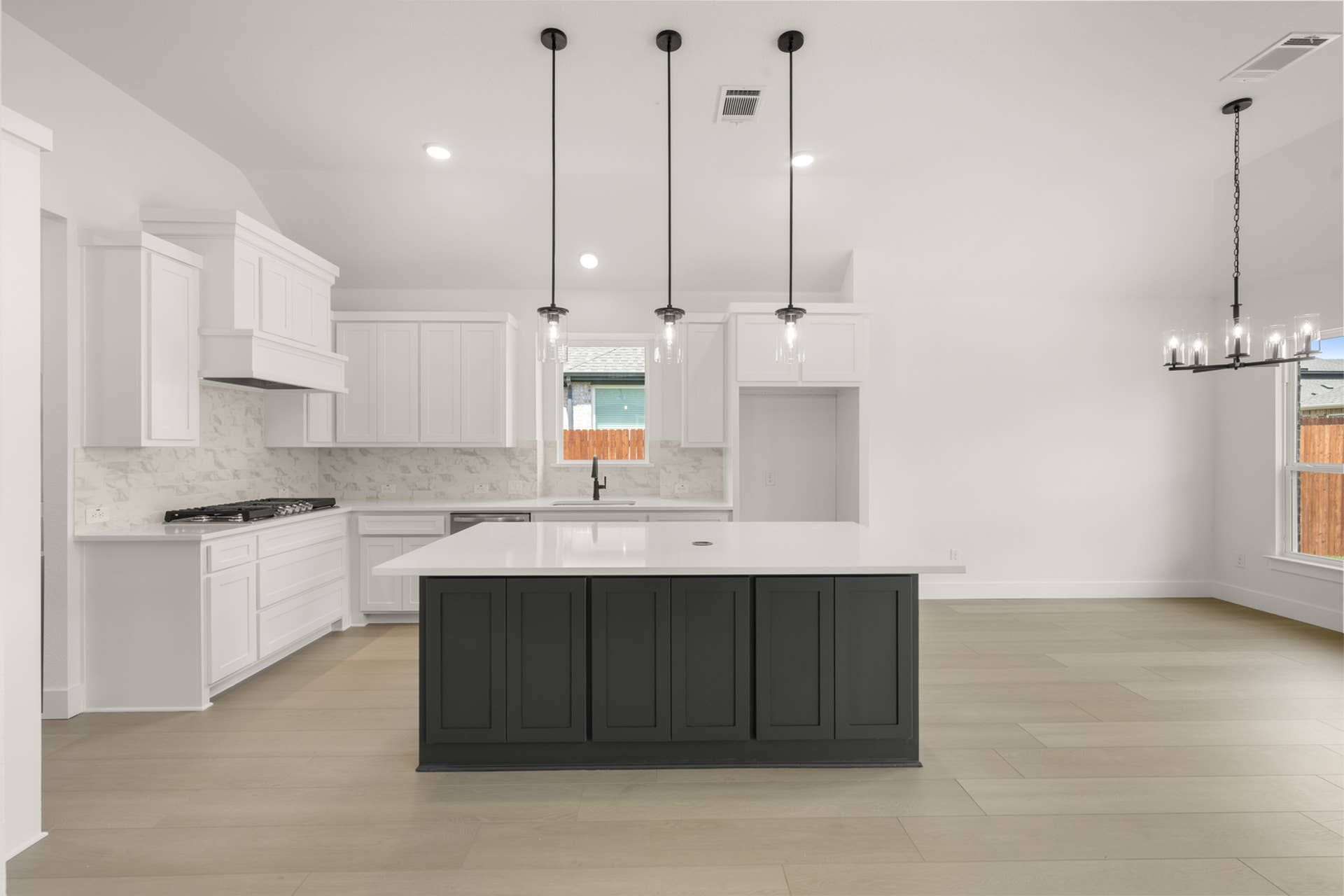 Modern kitchen with white cabinetry, island, and pendant lighting.