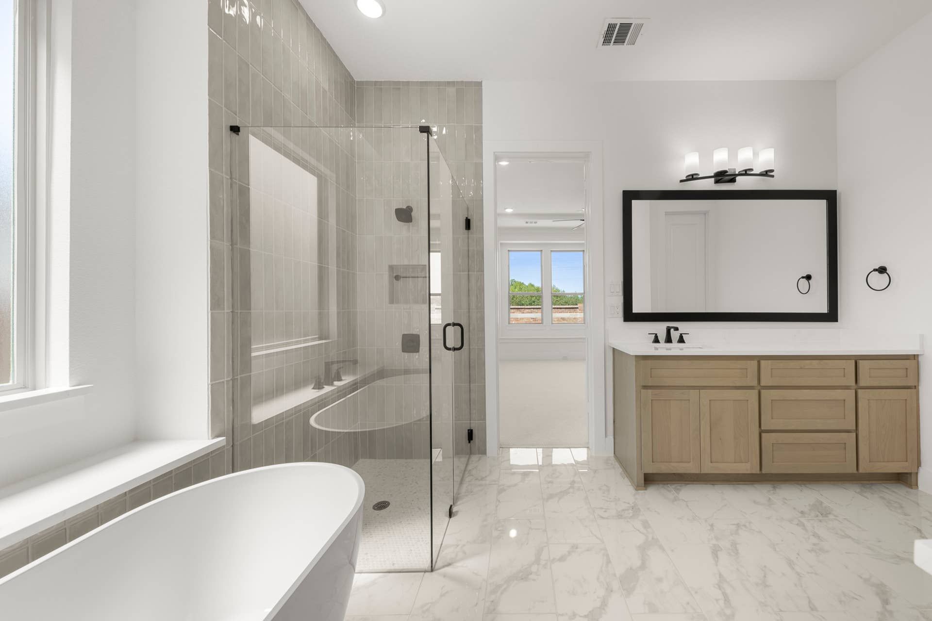 Modern bathroom with glass shower, freestanding tub, and wood vanity.