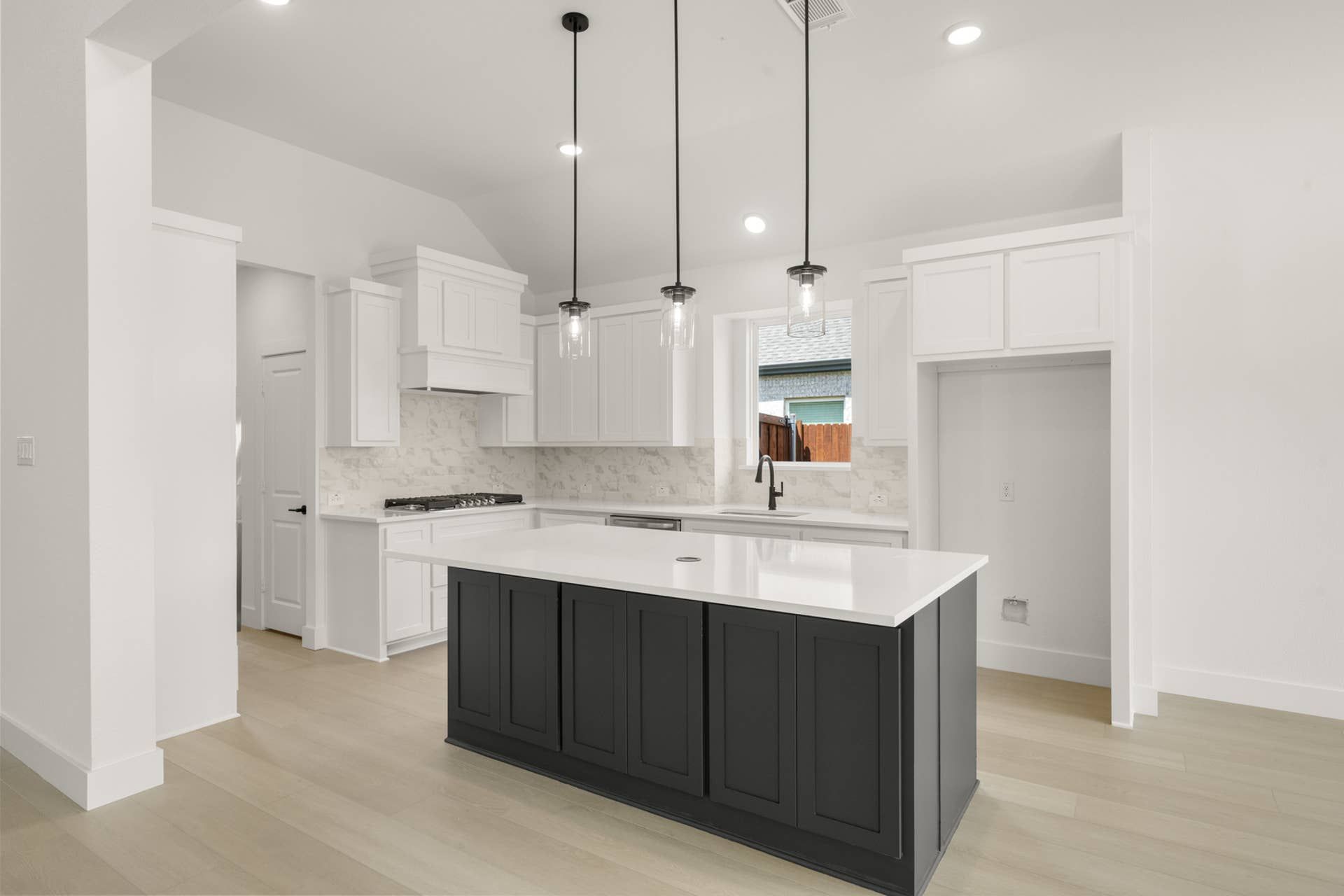 Modern kitchen with black island, white cabinets, and pendant lighting.