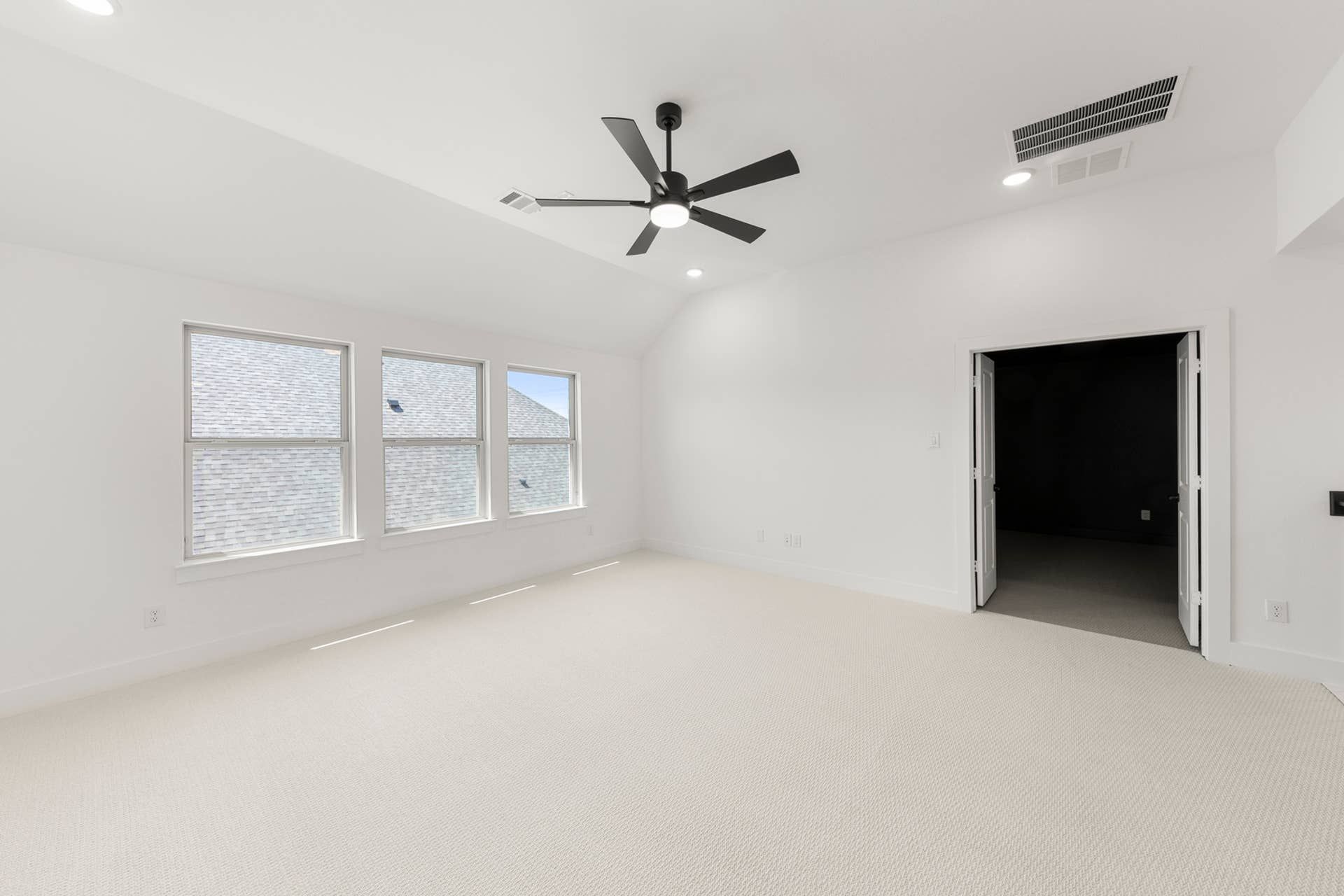 Spacious interior room with ceiling fan and large windows.