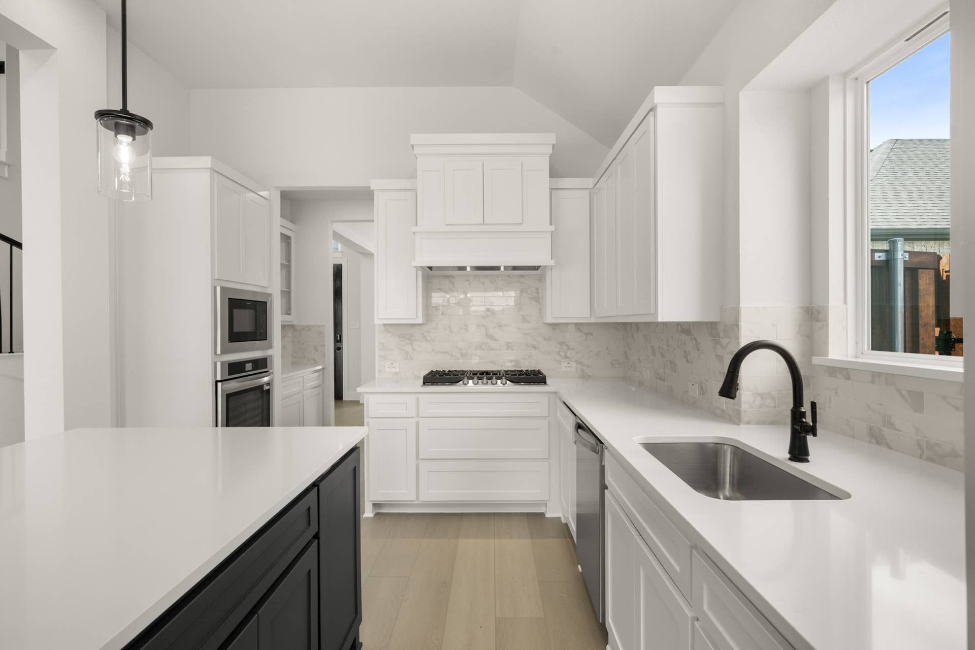 Modern kitchen with white cabinetry, marble backsplash, and stainless steel appliances.