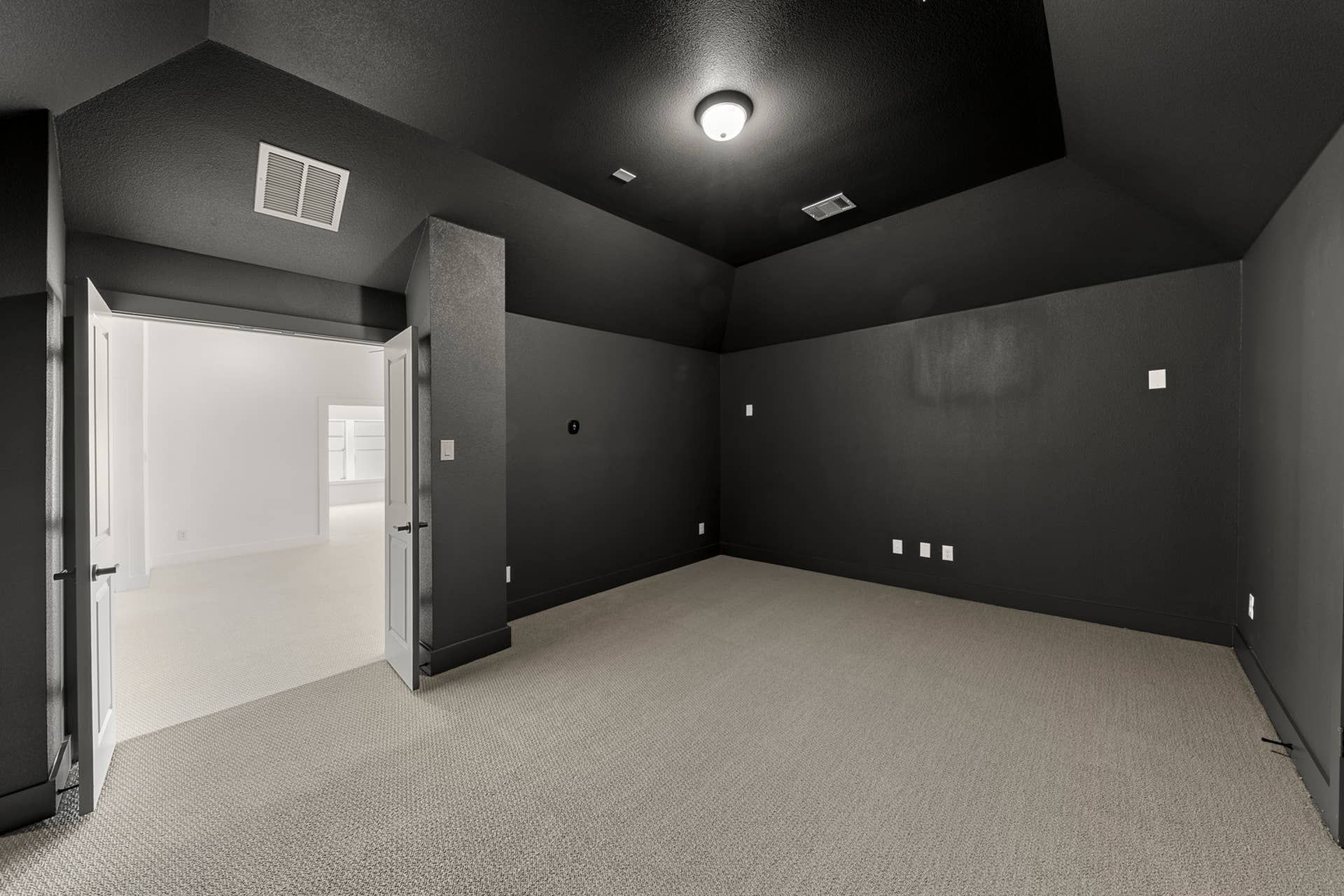 Interior room with dark walls and double doors leading to a bright area.