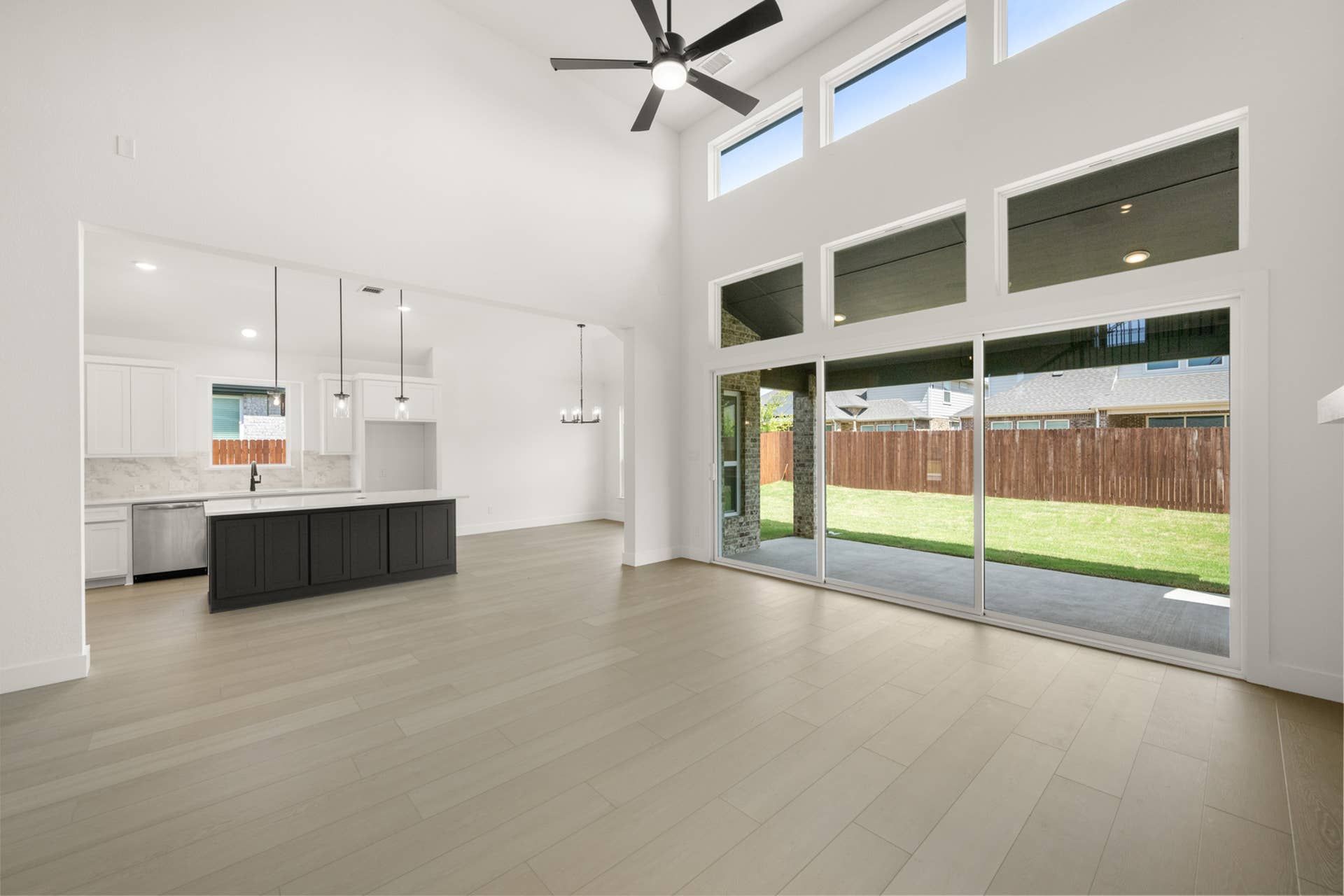 Spacious living room with high ceilings, large windows, and open kitchen layout.