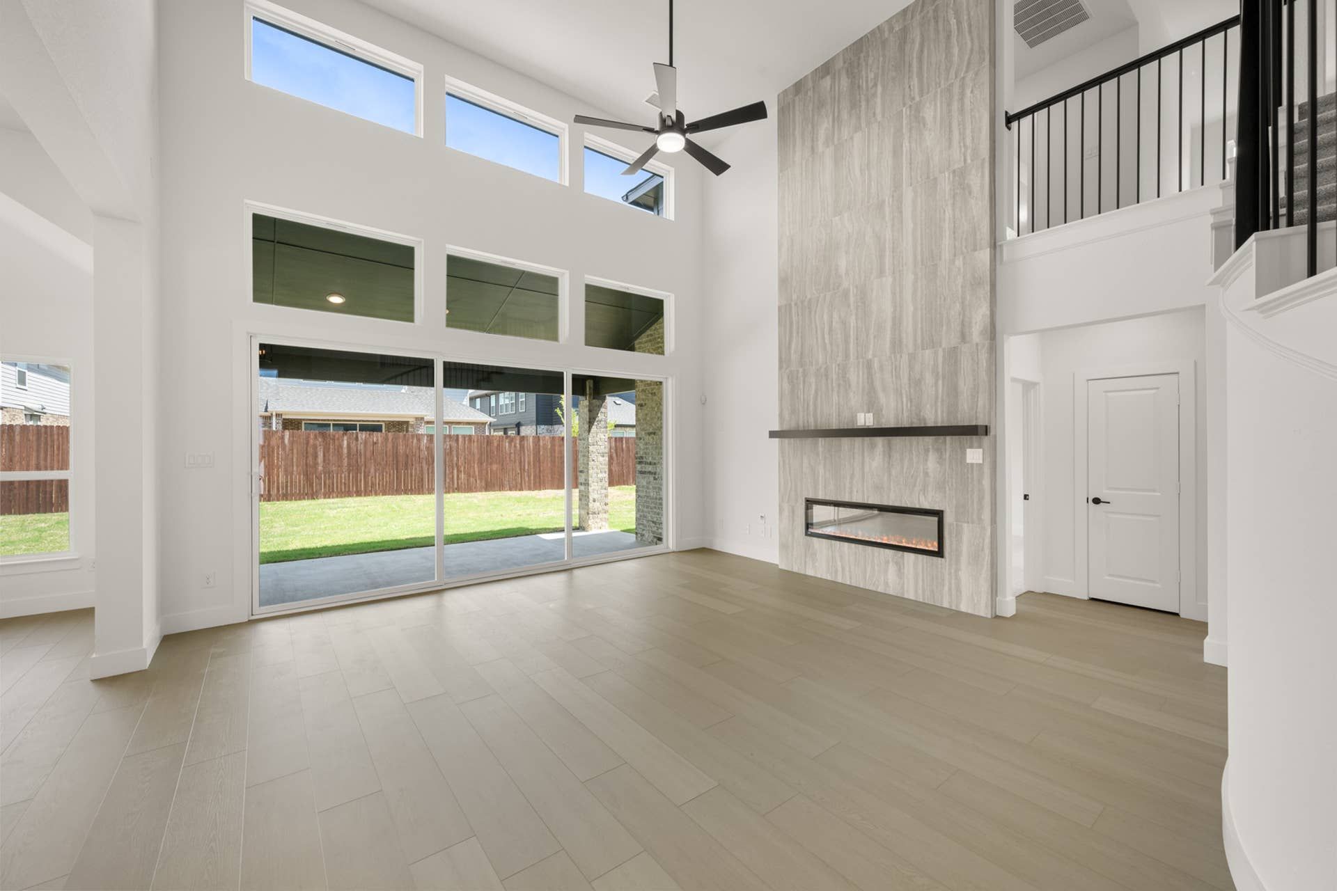 Spacious living room with high ceilings, large windows, and modern fireplace.