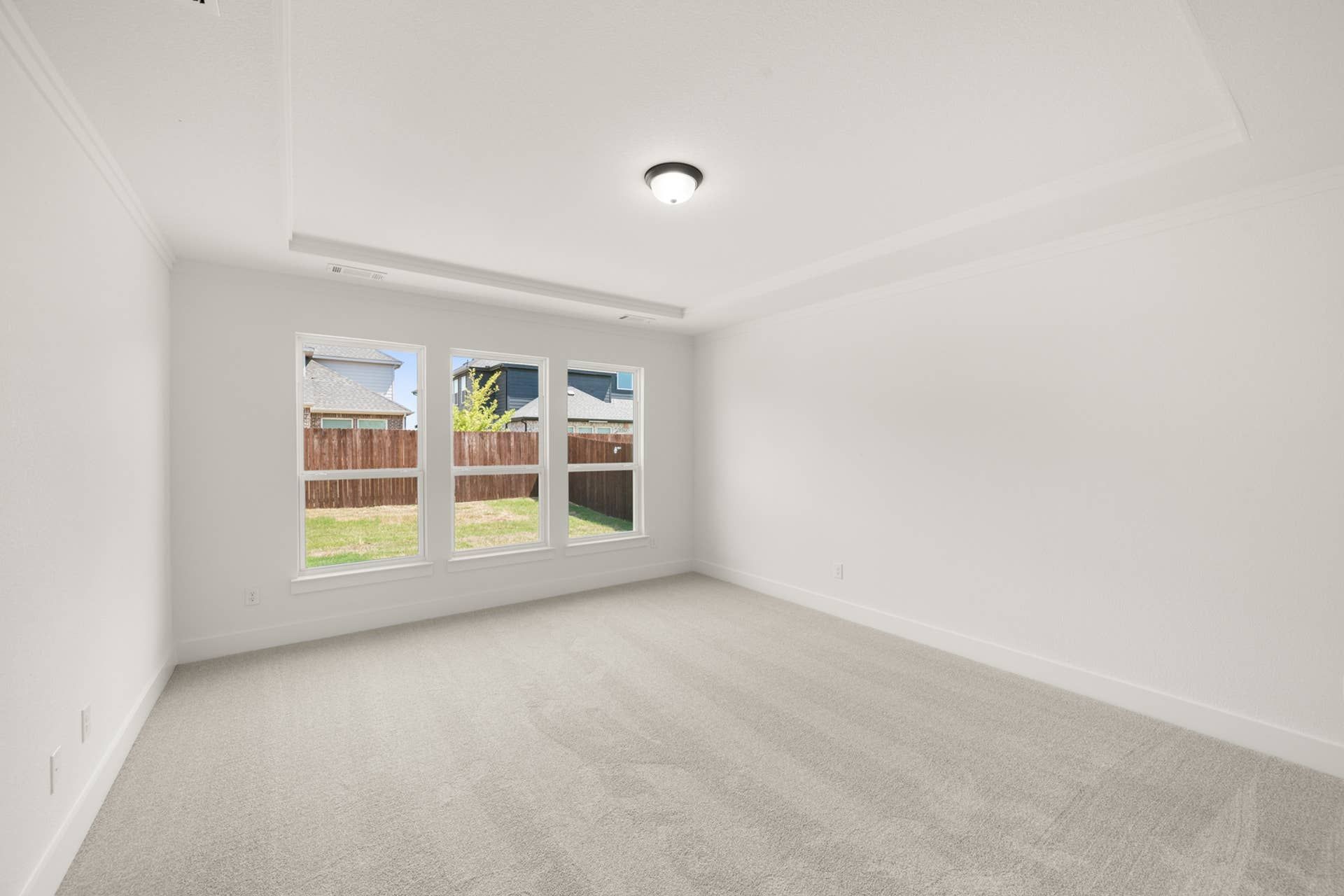 Bright primary suite with large windows and neutral carpet.