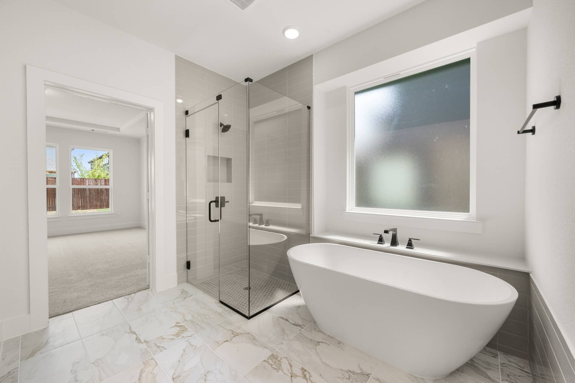 Luxurious bathroom with freestanding tub, glass shower, and large window.