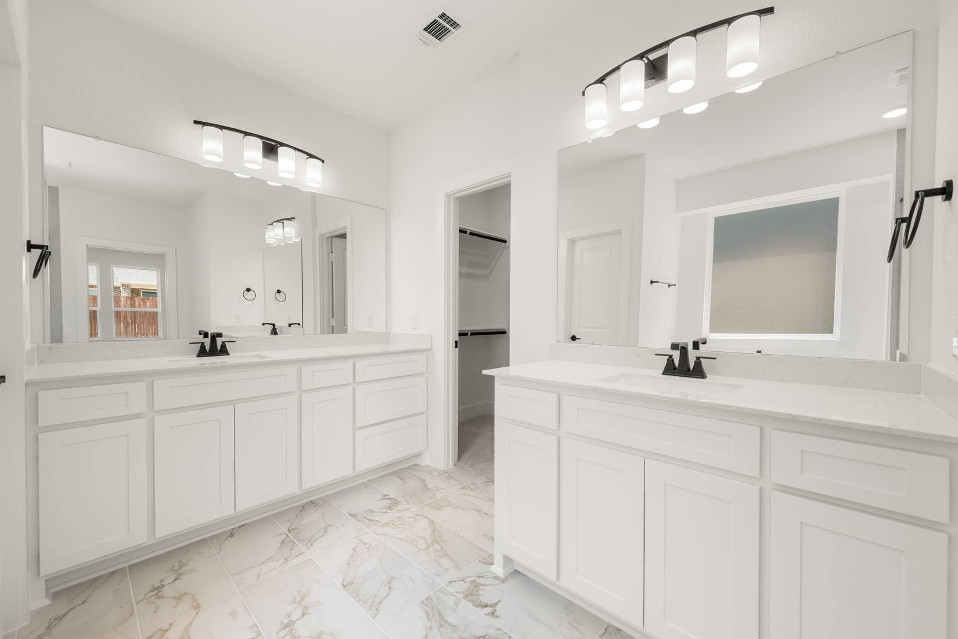 Elegant primary suite bathroom with double vanity and marble tile flooring.
