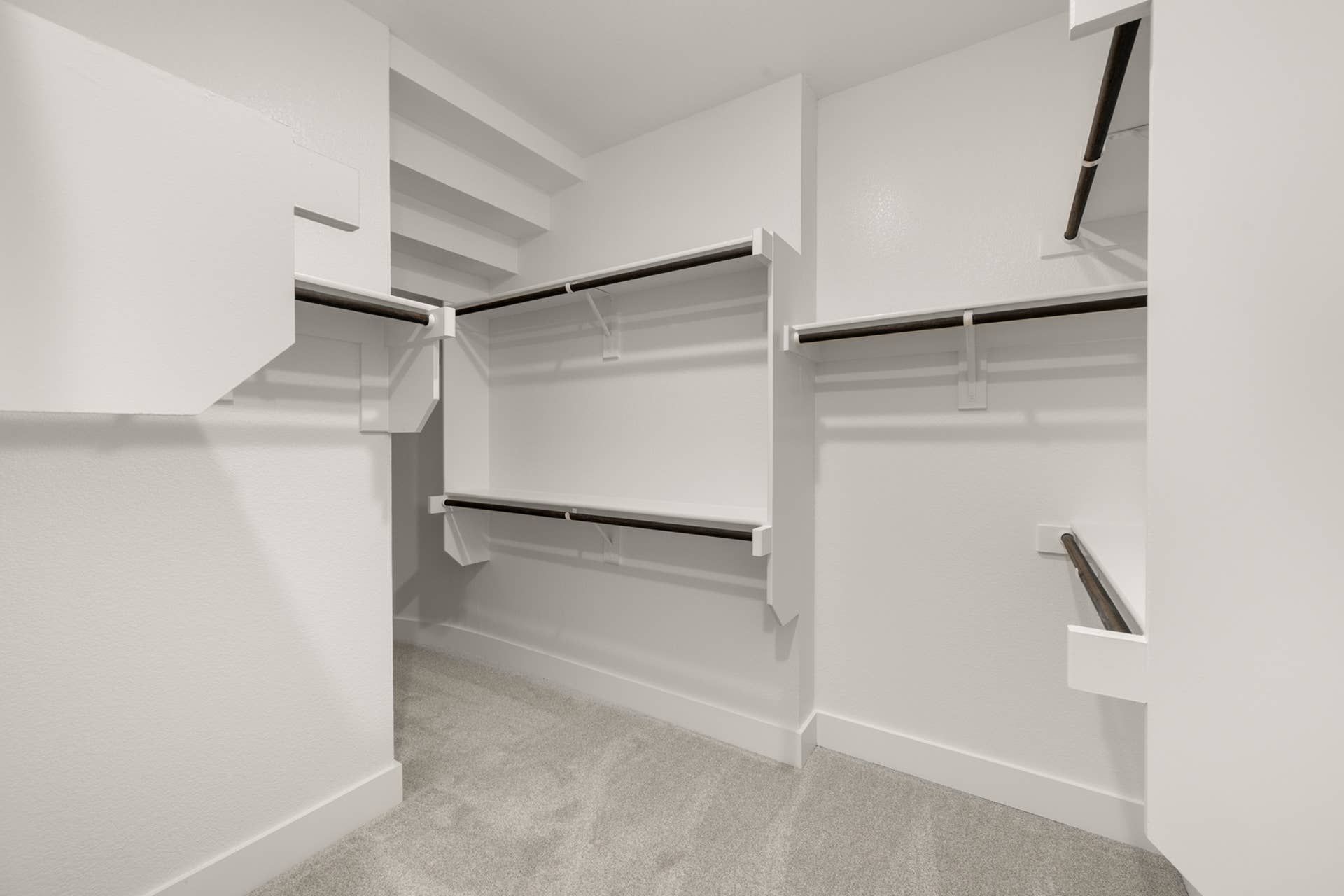 Spacious walk-in closet with white shelving and hanging rods.
