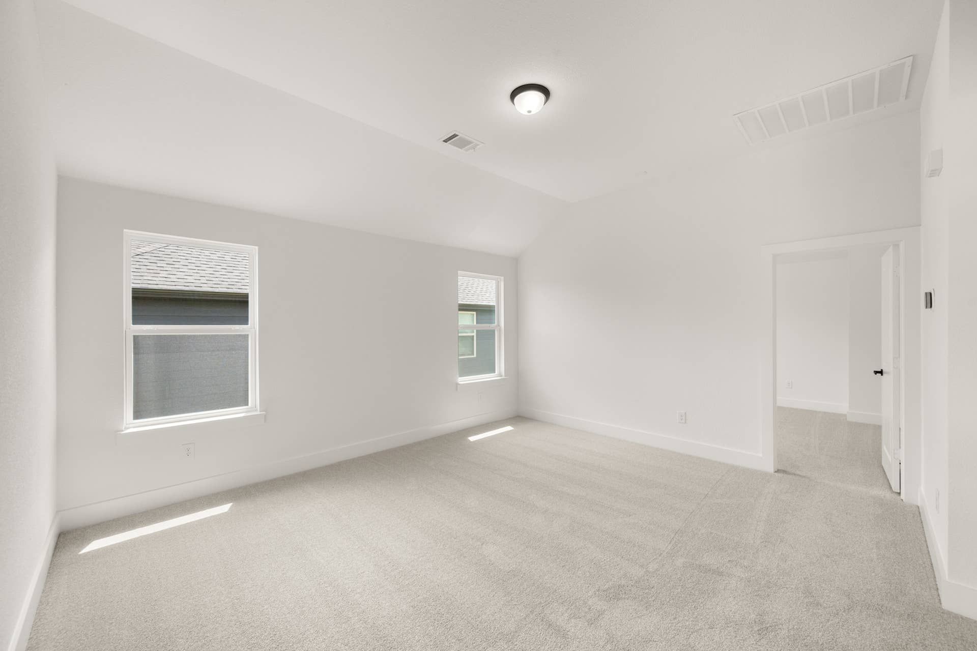 Spacious game room with neutral carpet and natural light from two windows.
