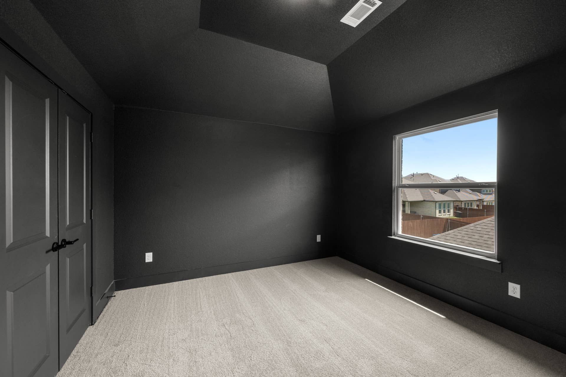 Modern media room with dark walls and large window view.