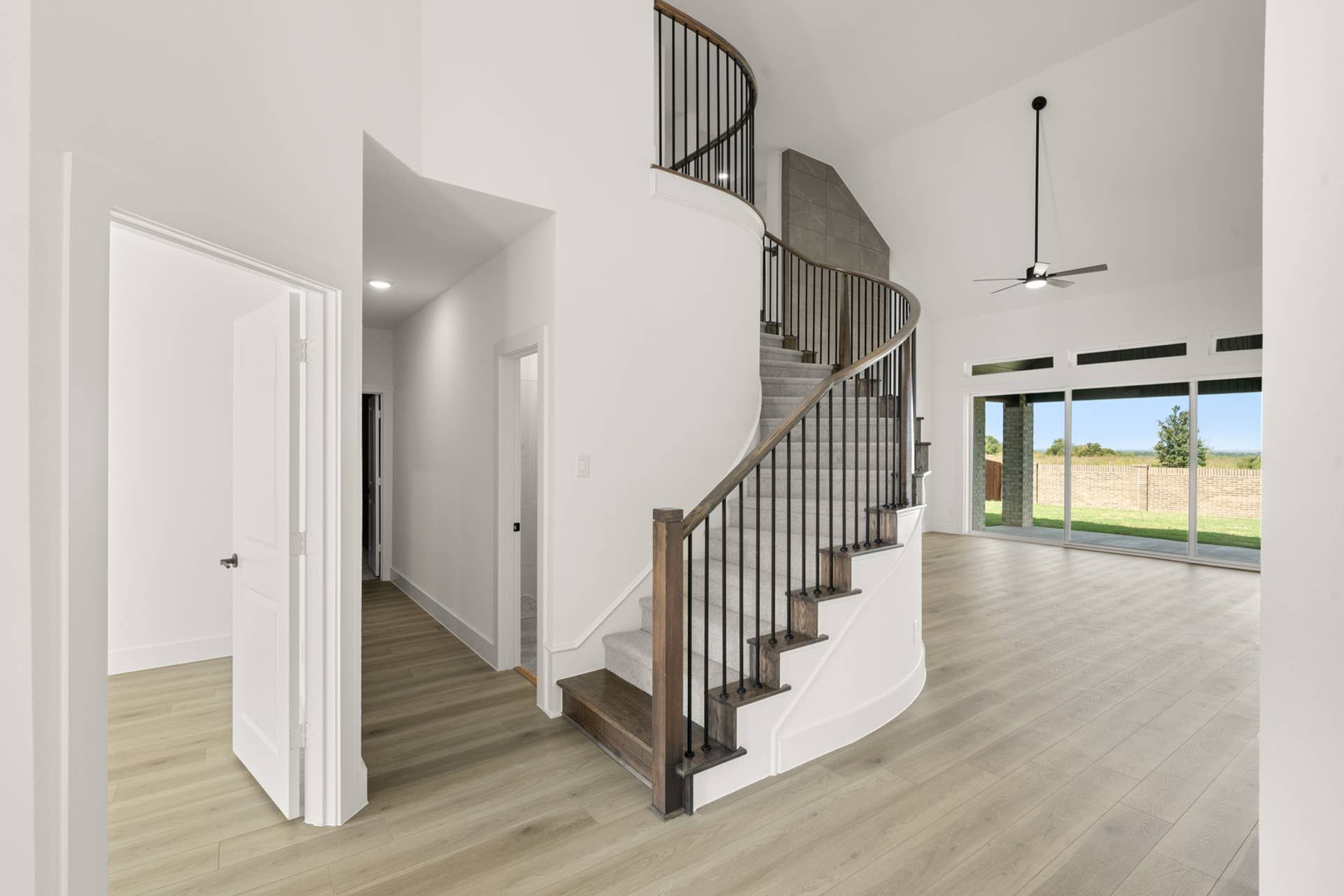 Elegant entry with curved staircase and large windows in modern home interior.