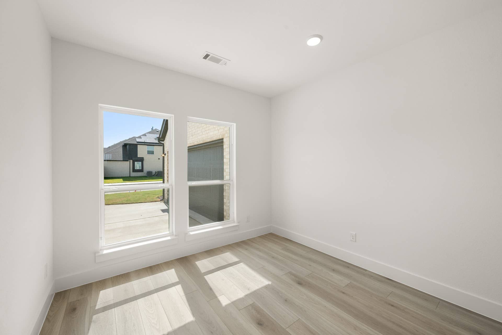 Bright study room with large windows and light wood flooring.