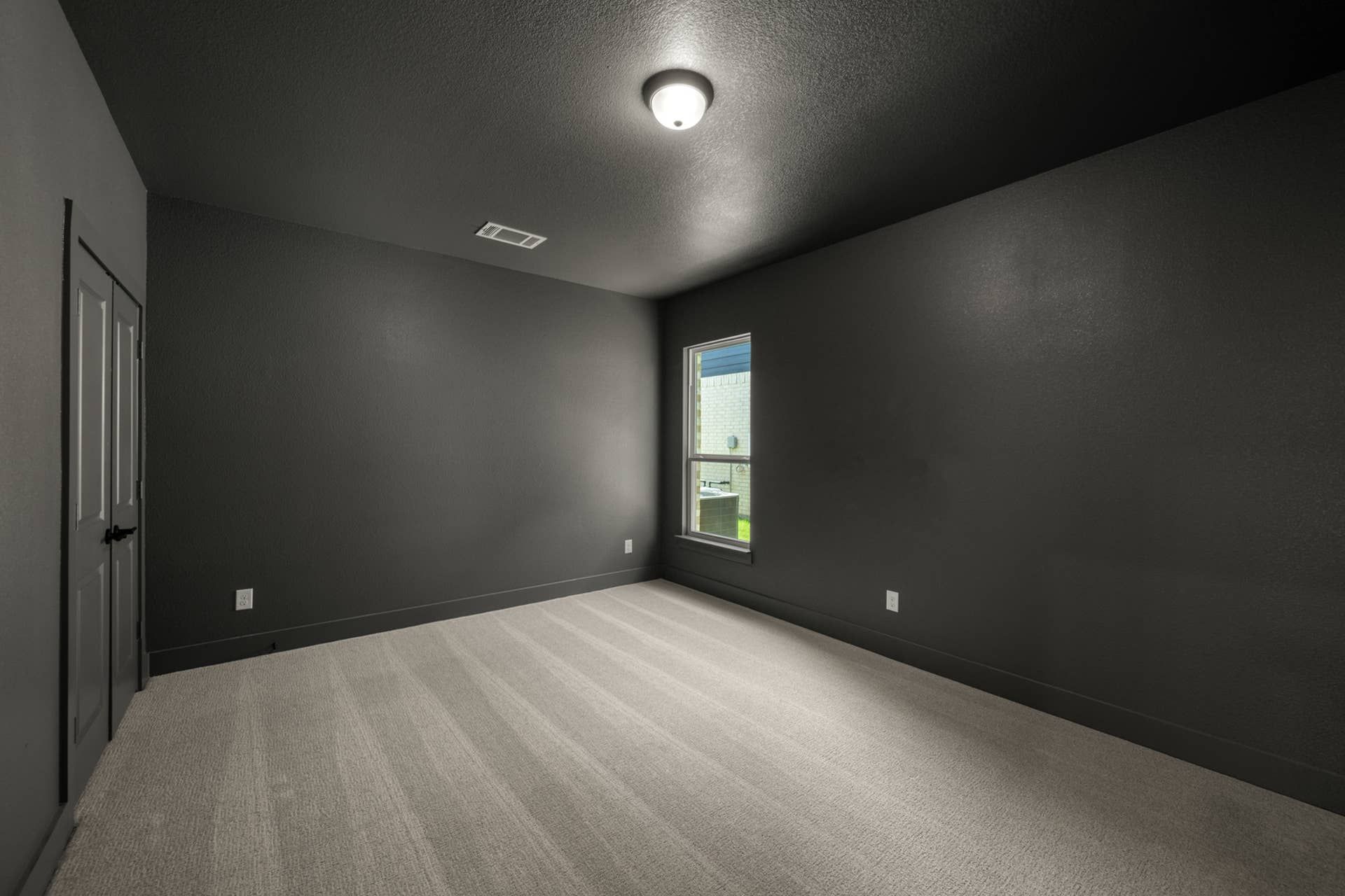 Dark-walled media room with carpeted floor and single window.