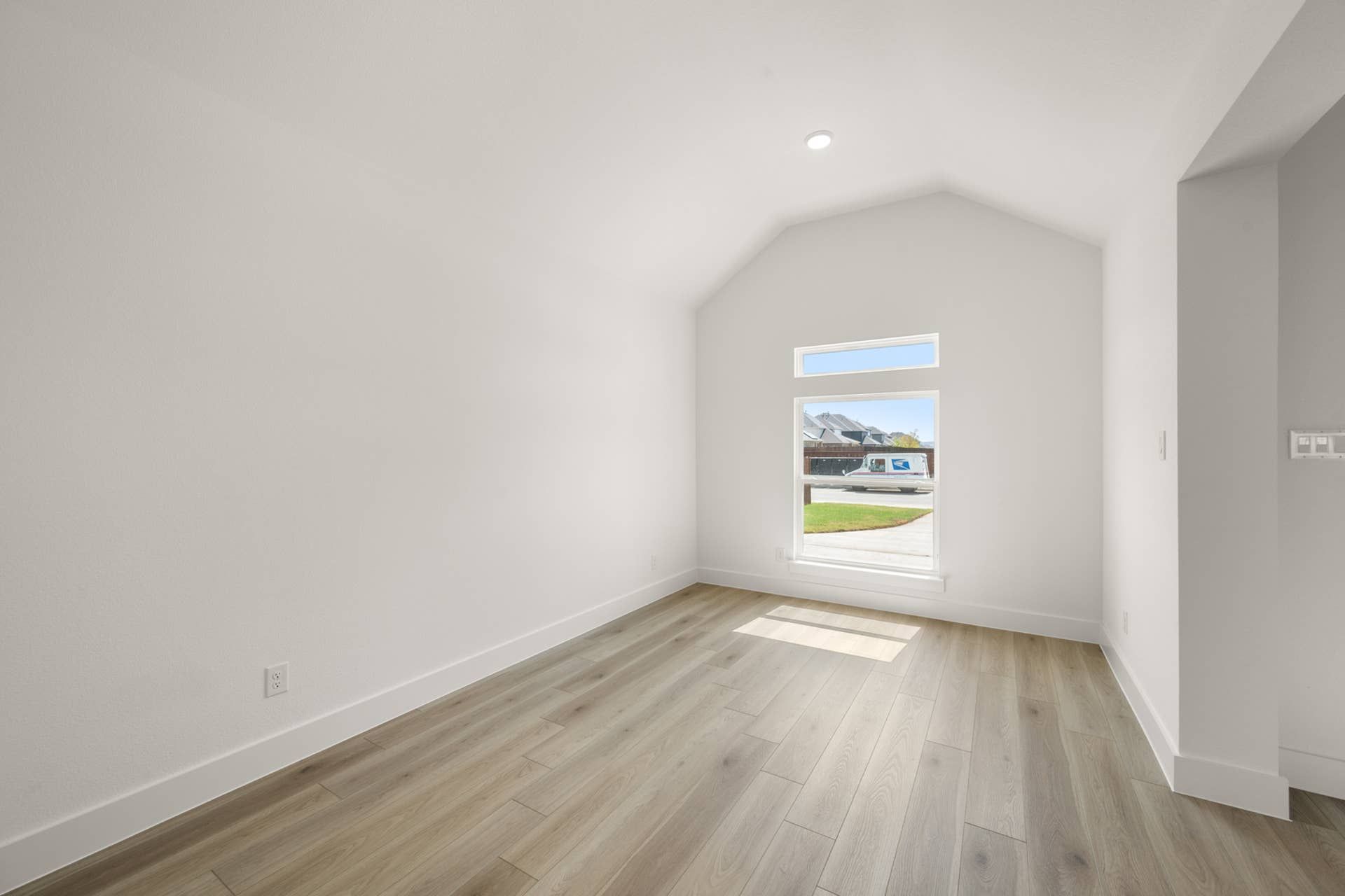 Bright interior room with vaulted ceiling and large window.