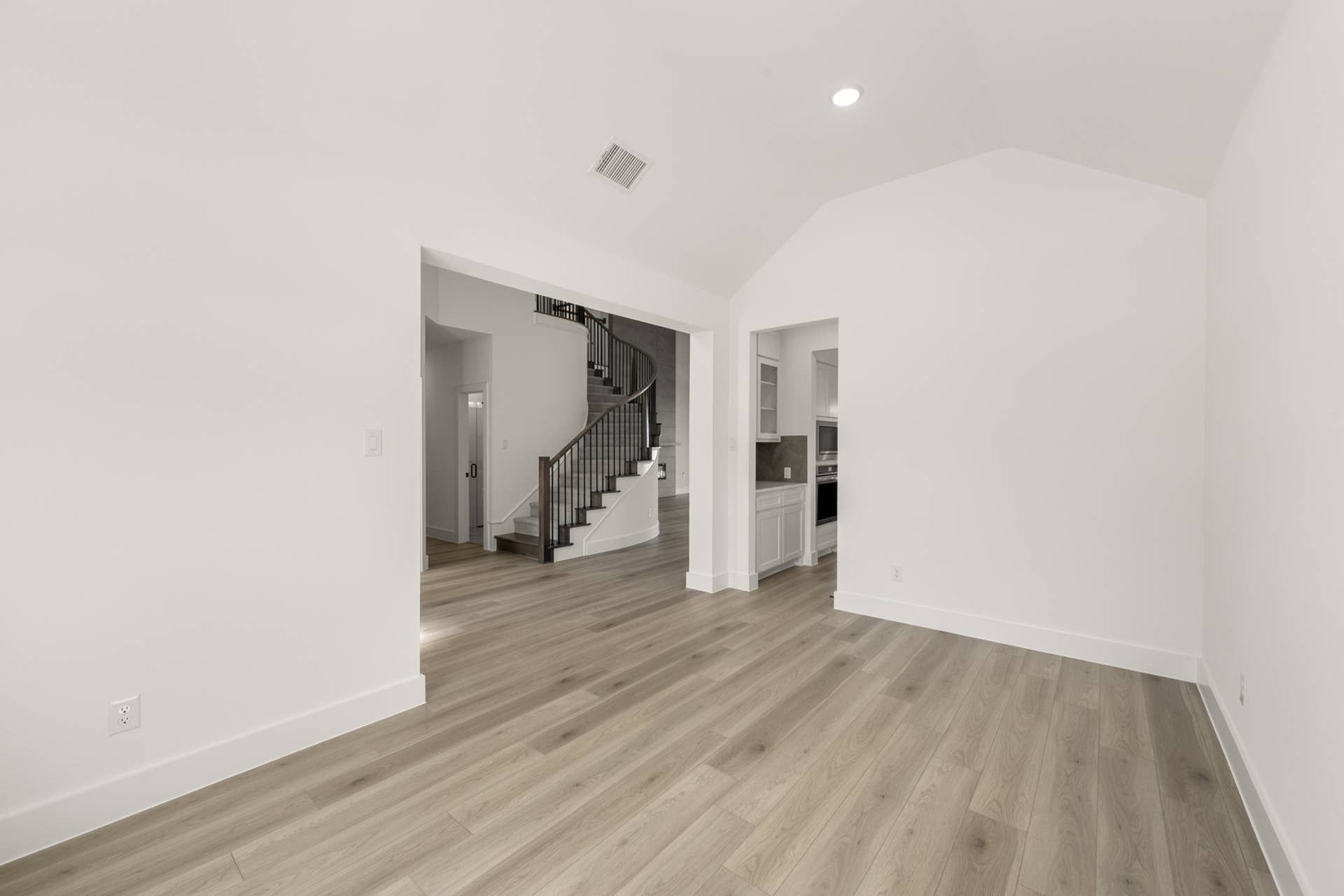 Spacious interior with wood flooring and elegant curved staircase.