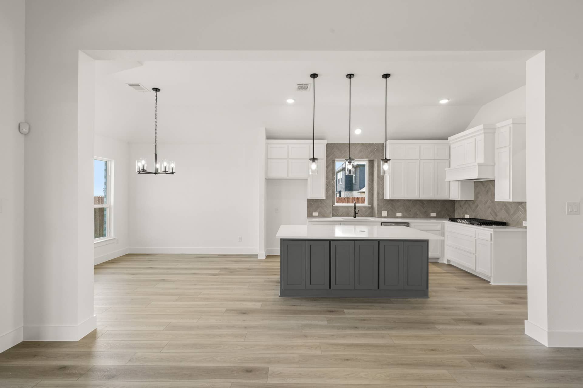 Spacious modern kitchen with island, pendant lights, and herringbone backsplash.