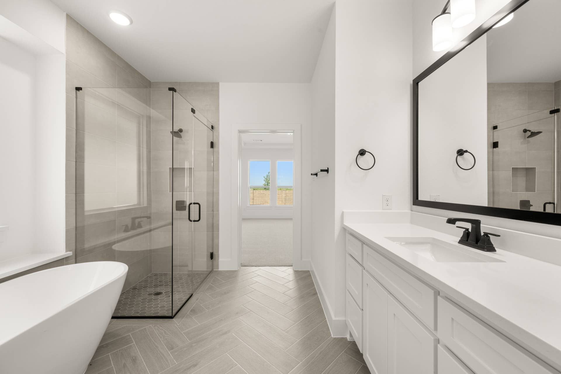 Modern bathroom with glass shower, freestanding tub, and large vanity mirror.