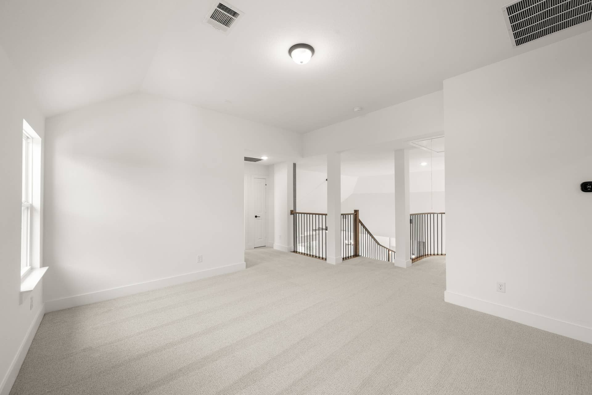 Spacious game room with carpet flooring and natural light.
