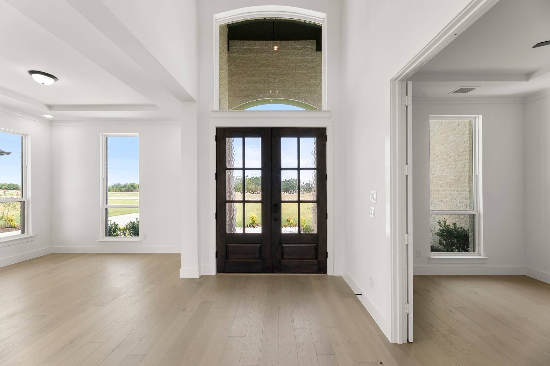 Spacious entryway with wooden double doors and large windows.