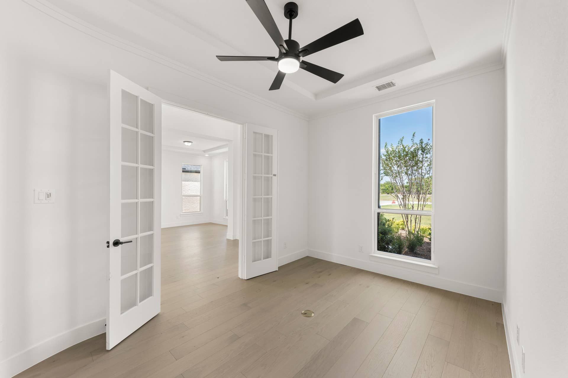 Bright study room with French doors and large window overlooking garden.