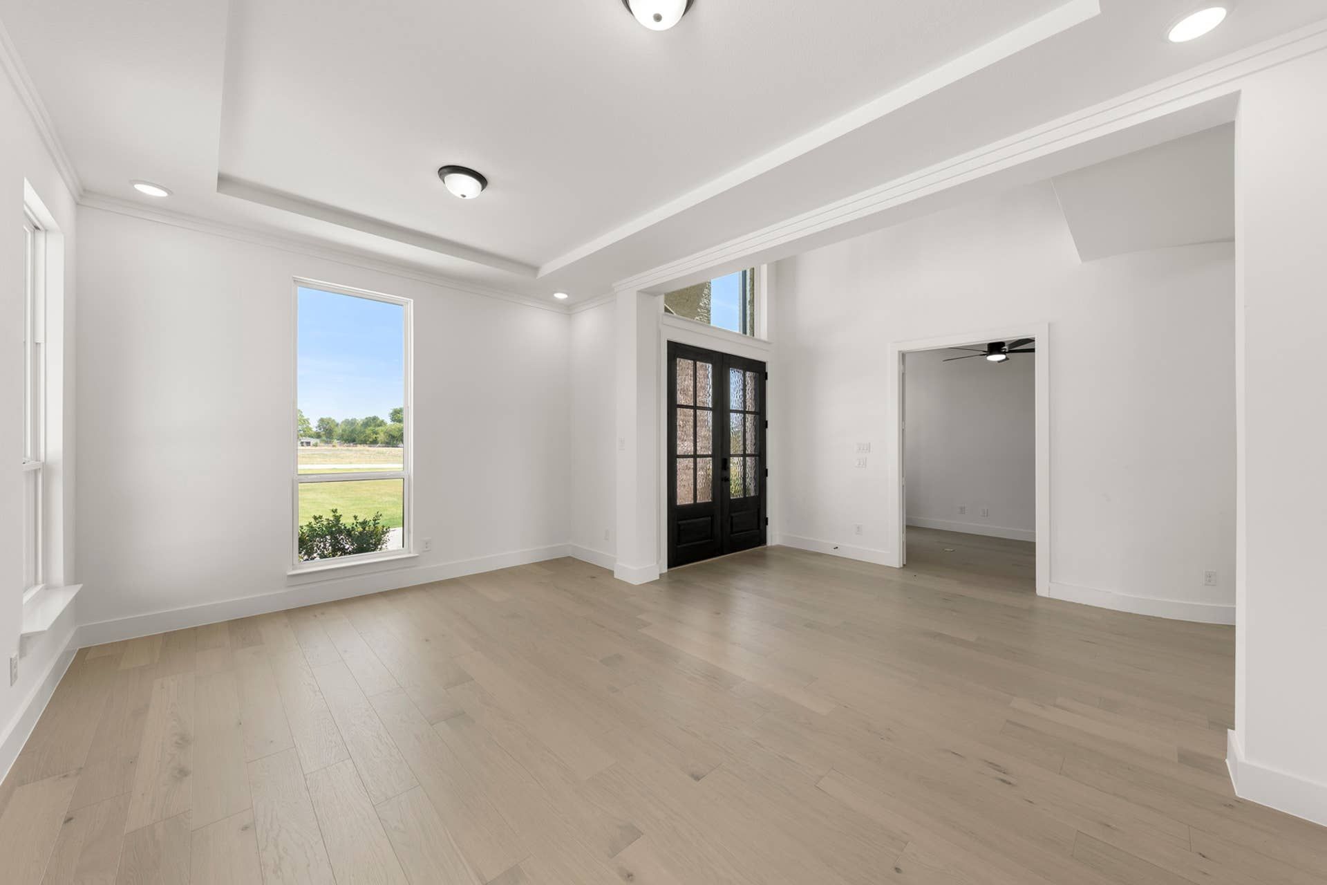 Spacious dining room with large window and elegant dark double doors.