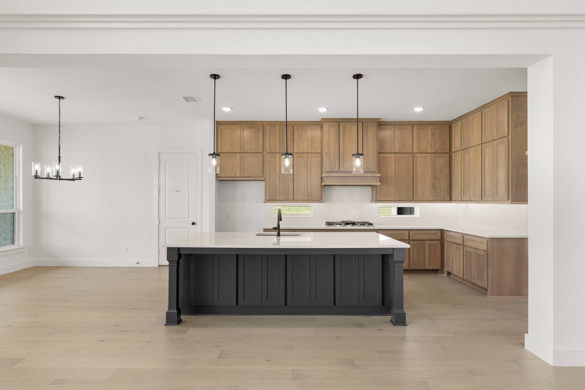 Modern kitchen with wooden cabinetry, large island, and pendant lighting.