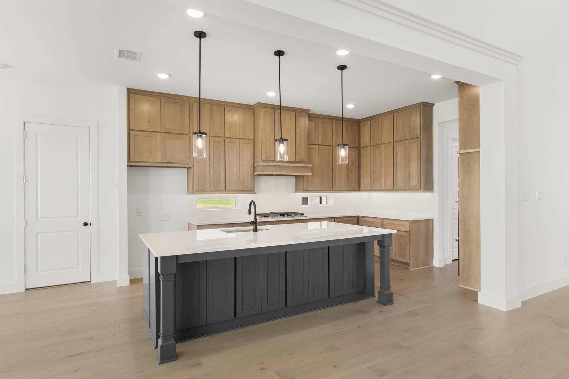 Modern kitchen with wood cabinetry, pendant lights, and central island.