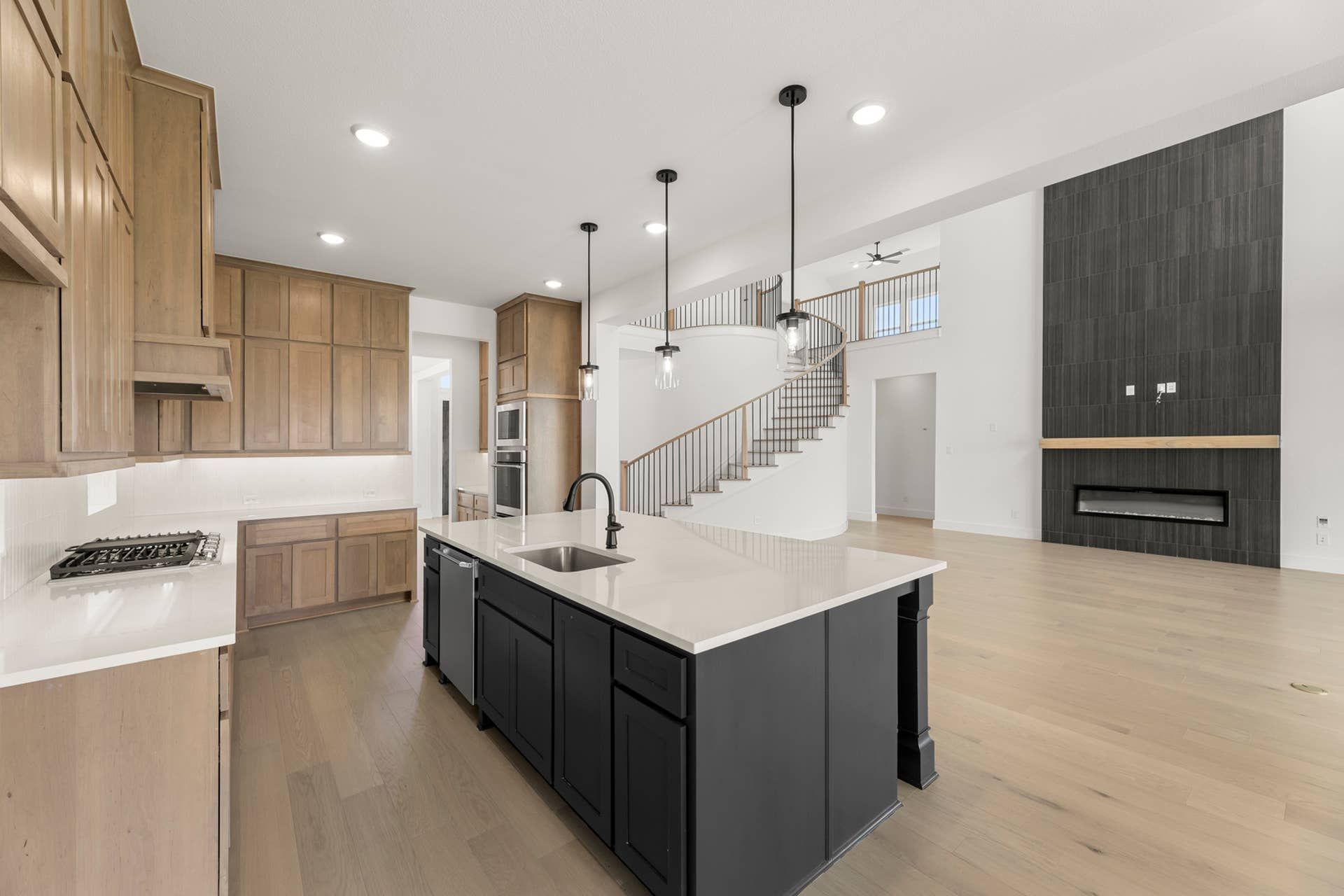 Spacious kitchen with modern island, pendant lighting, and open staircase view.