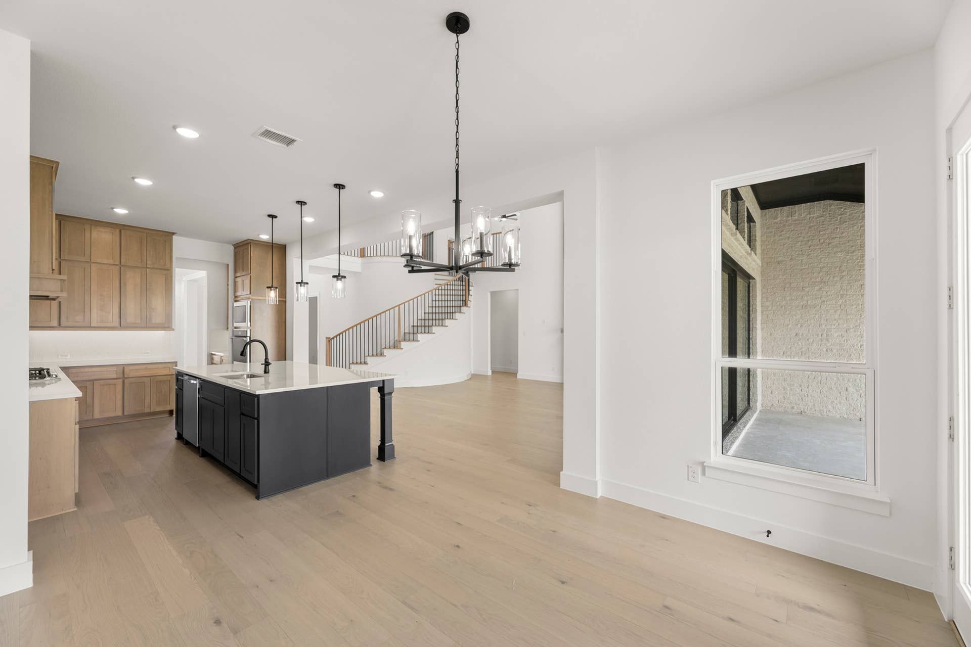 Spacious open-concept kitchen with island, modern lighting, and adjacent dining area.