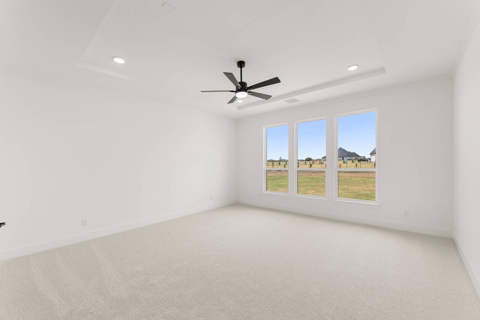 Spacious bedroom with large windows, ceiling fan, and recessed lighting.