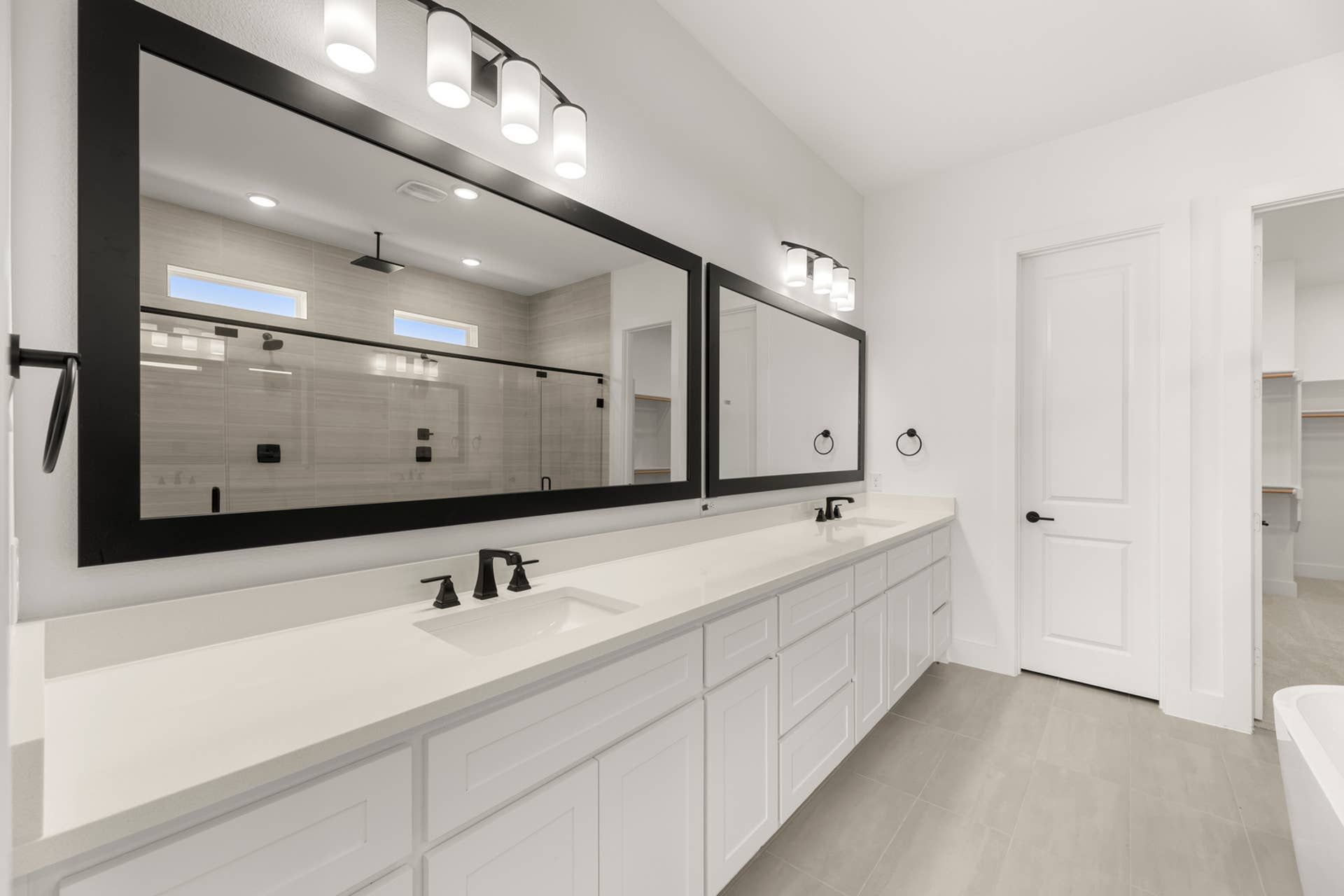 Modern bathroom with double vanity, framed mirrors, and sleek black fixtures.