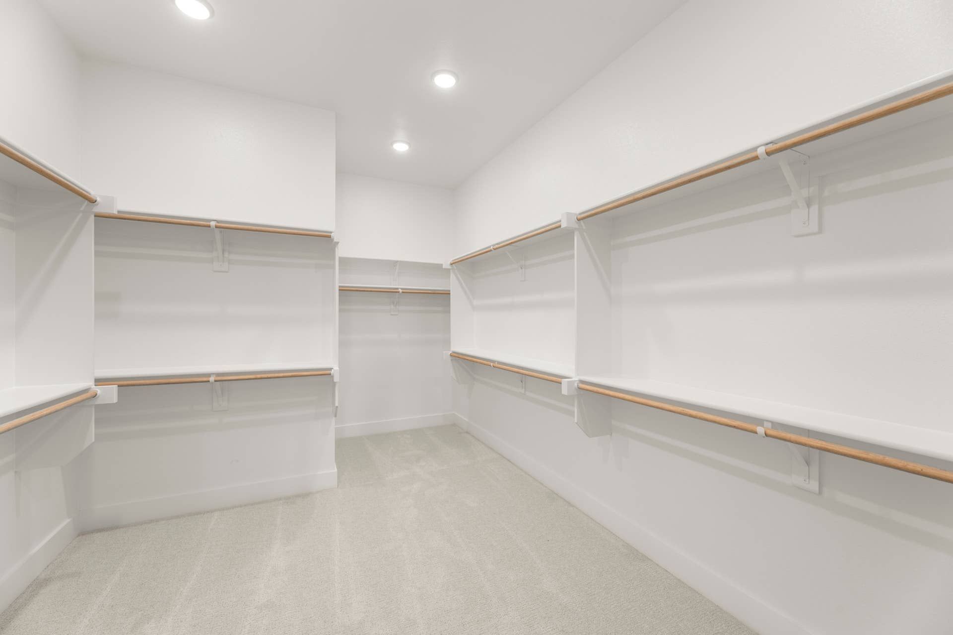 Spacious walk-in closet with built-in shelves and carpeted flooring.